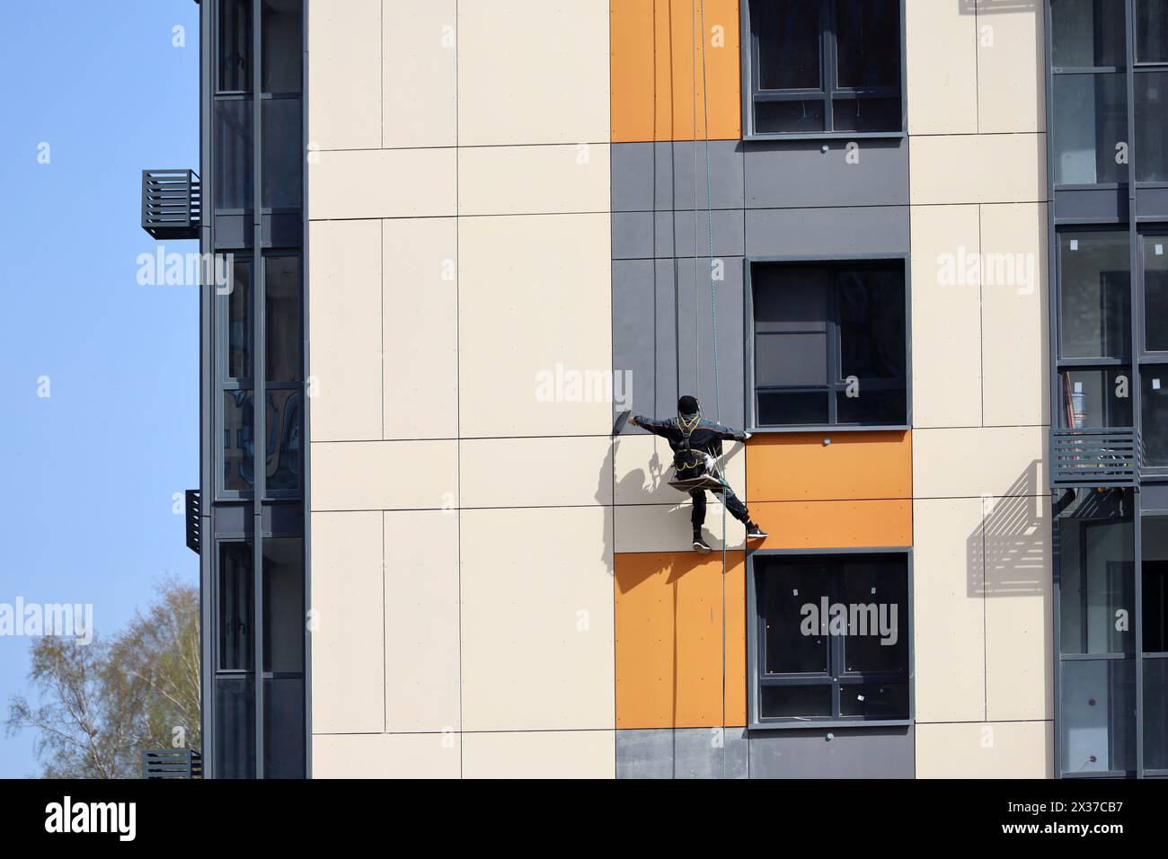 Fensterreiniger an der Hochhausfassade. Der Arbeiter wäscht die Wand und die Fenster an der Wolkenkratzerwand Stockfoto