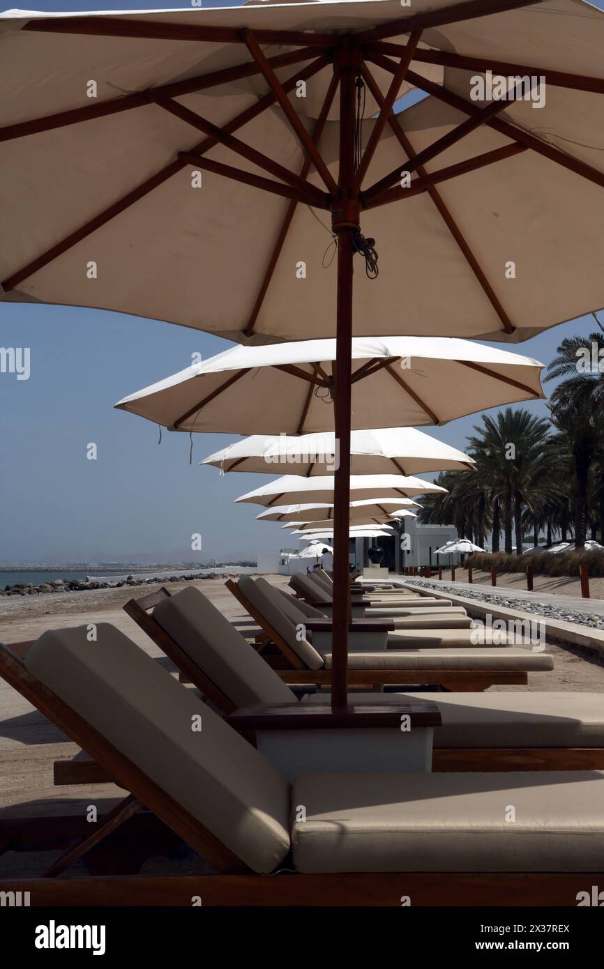 Leere Sonnenliegen und Sonnenschirme am Strand im Chedi Hotel Muscat Oman Stockfoto