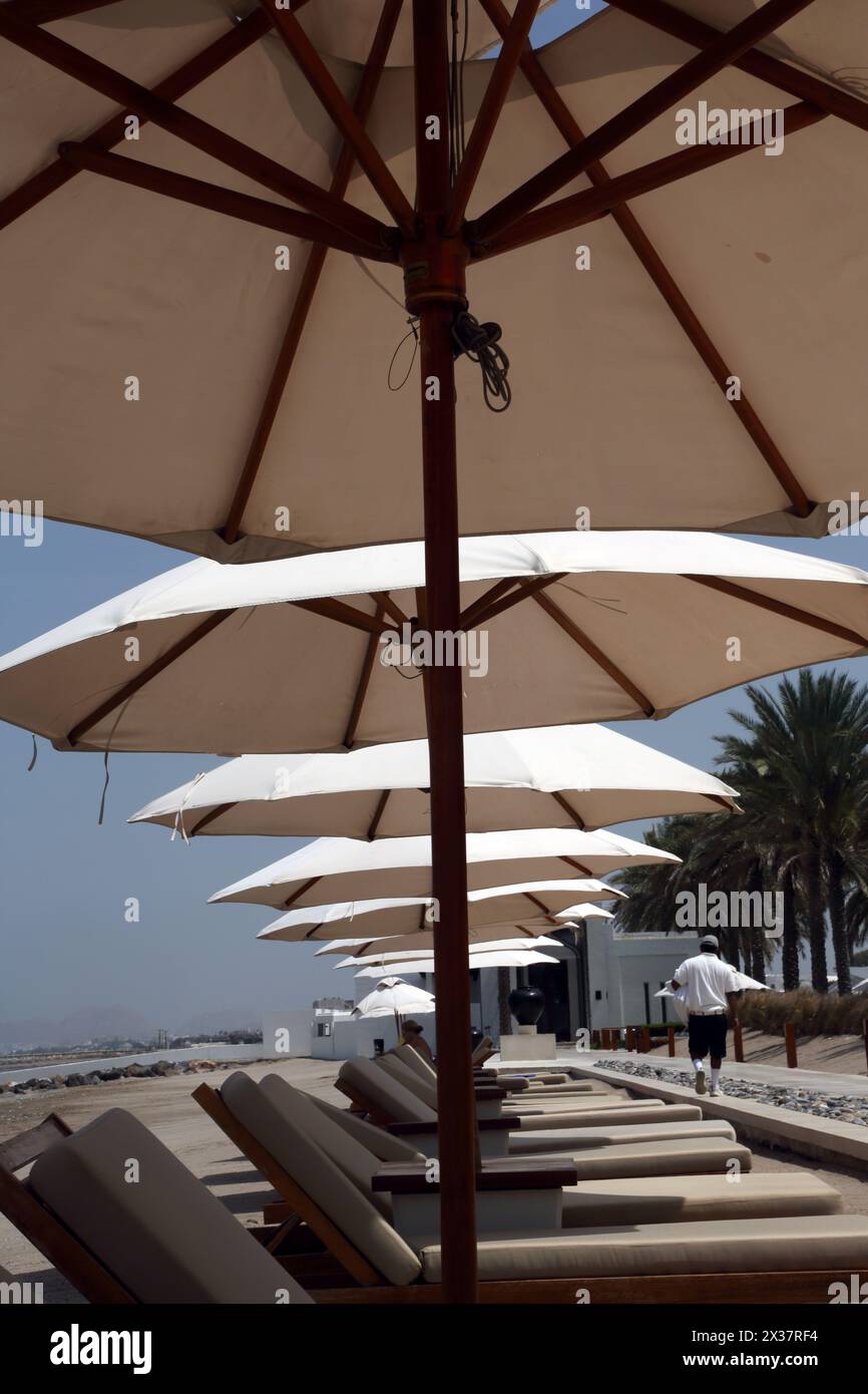 Leere Sonnenliegen und Sonnenschirme am Strand im Chedi Hotel Muscat Oman Stockfoto