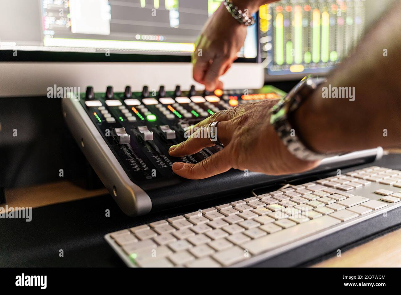 Nahaufnahme der Tontechniker-Hände, die die Bedienelemente an einer Tonmischkonsole anpassen – Präzision und Erfahrung in der Aufnahme und Produktion von Musik-Audio. Stockfoto