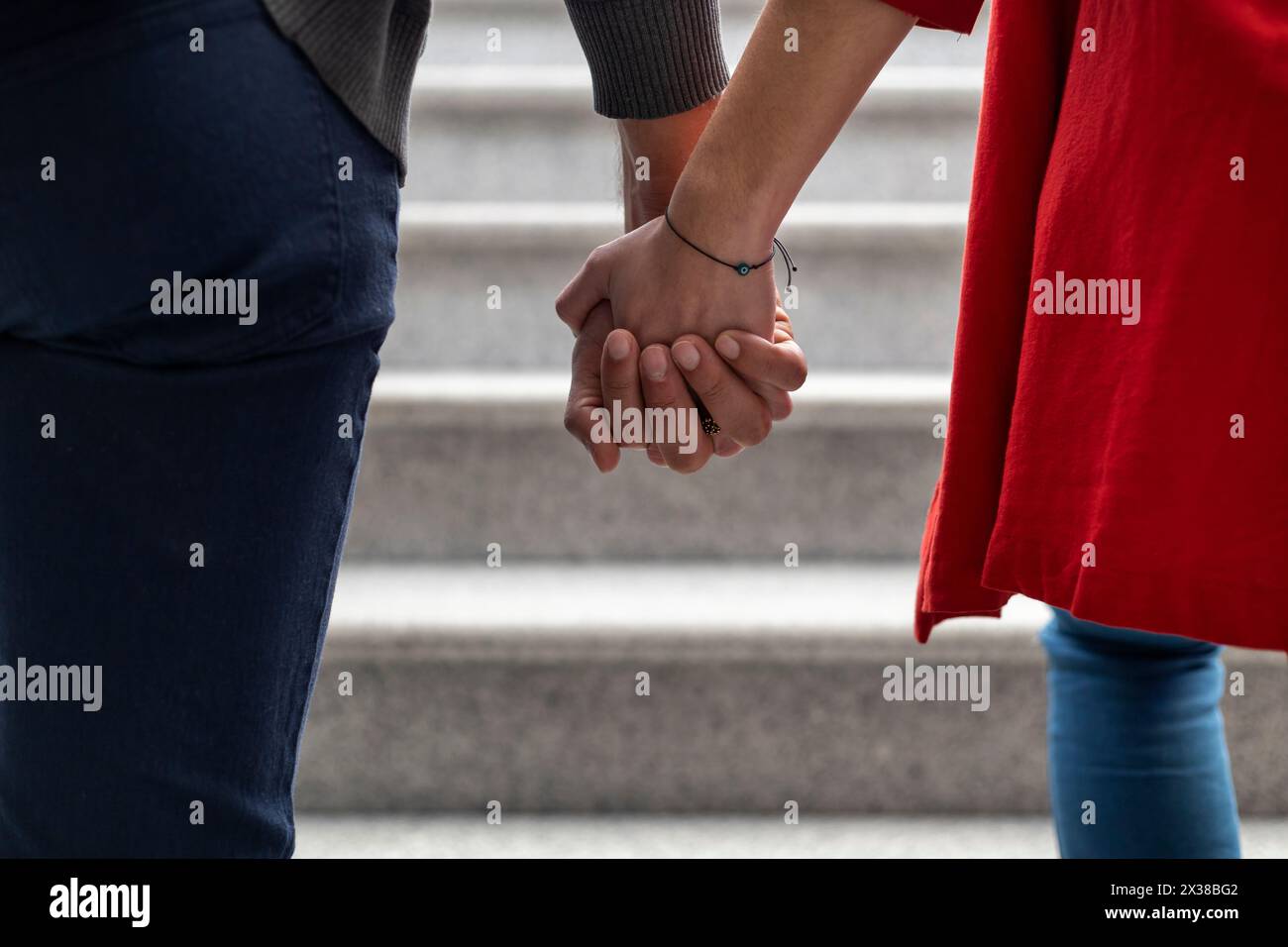 Unerkennbares, junges lateinamerikanisches Paar, das rückwärts geht und Hände hält. Mittlere Nahaufnahme ihrer ineinander verflochtenen Hände. Konzept von Liebe und Relaxatio Stockfoto