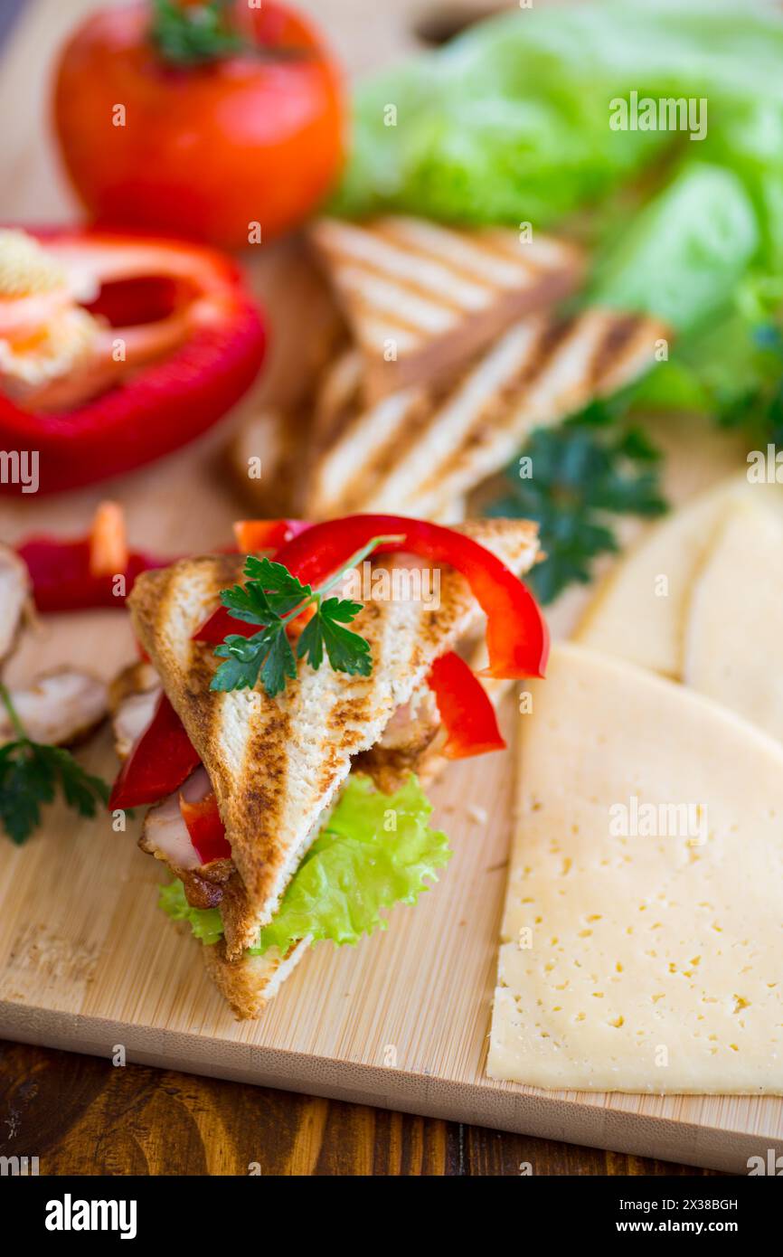 Gebratener Toast mit Huhn, Salat, Gemüse auf einem Holztisch. Stockfoto