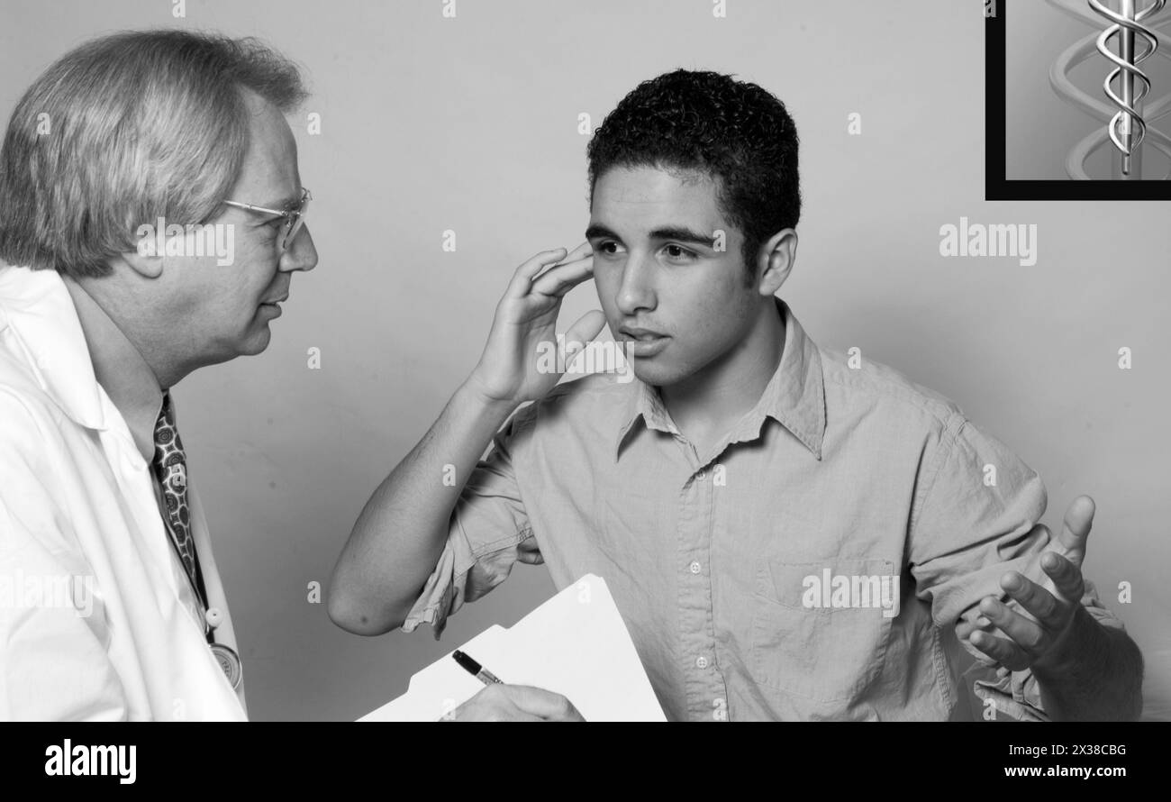Hausarzt, der mit Teen Boy über Earache redet Stockfoto