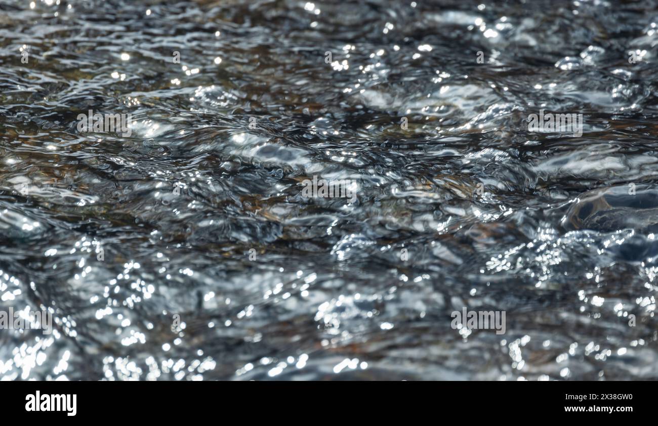 Frowing Bachwasseroberfläche mit abstraktem Welligkeitsmuster. Natürliches unscharfes Hintergrundfoto Stockfoto