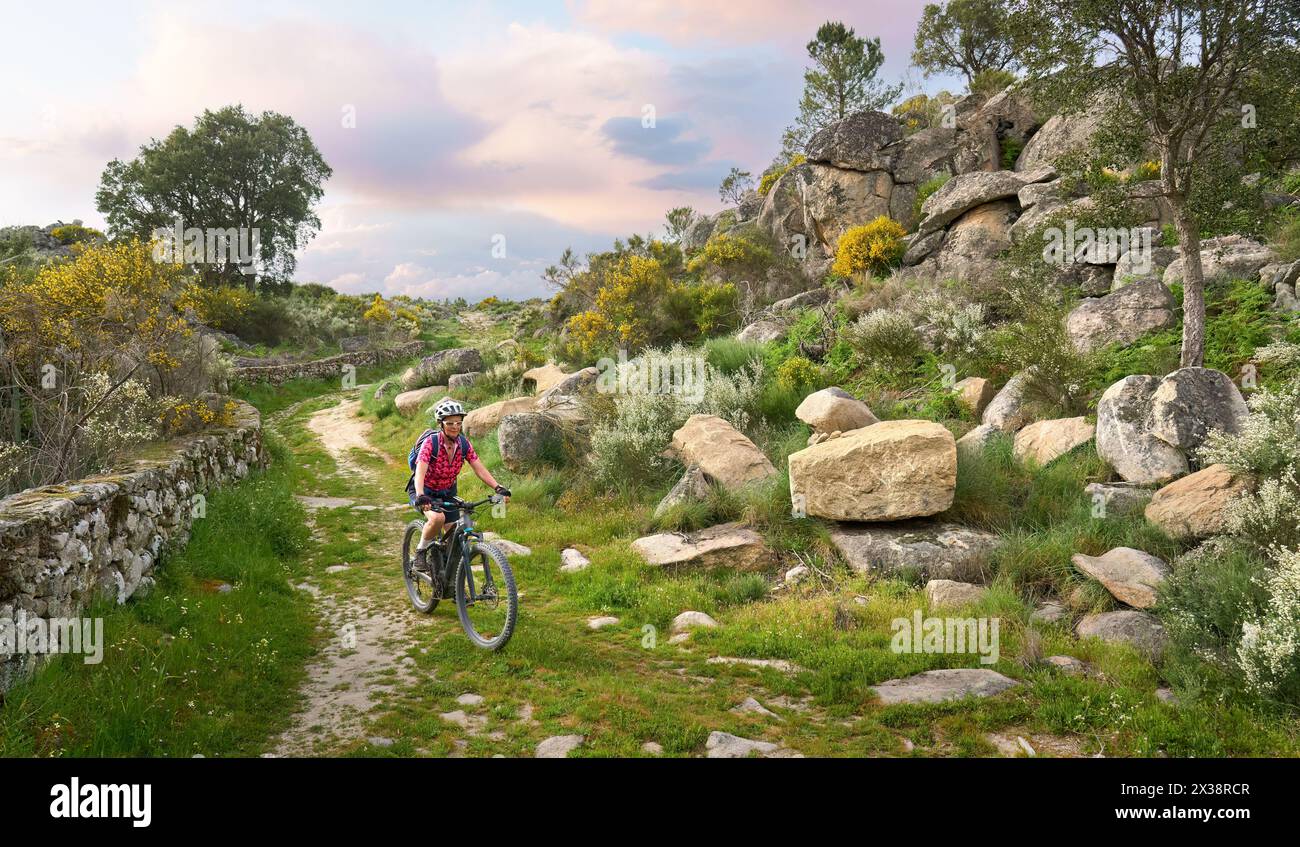 Aktive Seniorin radelt mit ihrem E-Mountainbike in der rauen Landschaft des Nationalparks Serra de São Mamede in der Nähe von Marvao im Zentrum Portugals Stockfoto