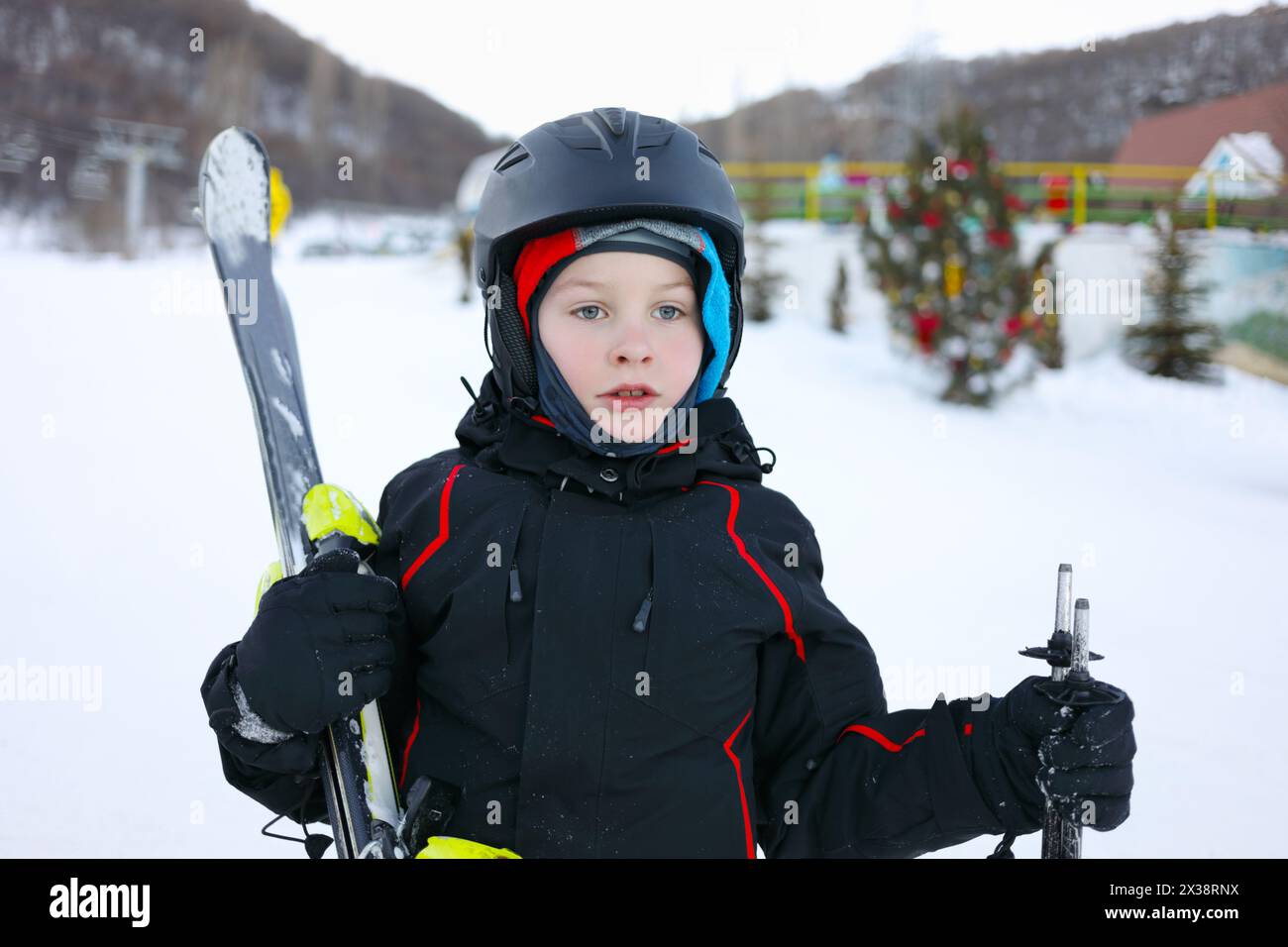 Junge im Helm mit Bergskistand im Skigebiet mit Bergen Stockfoto