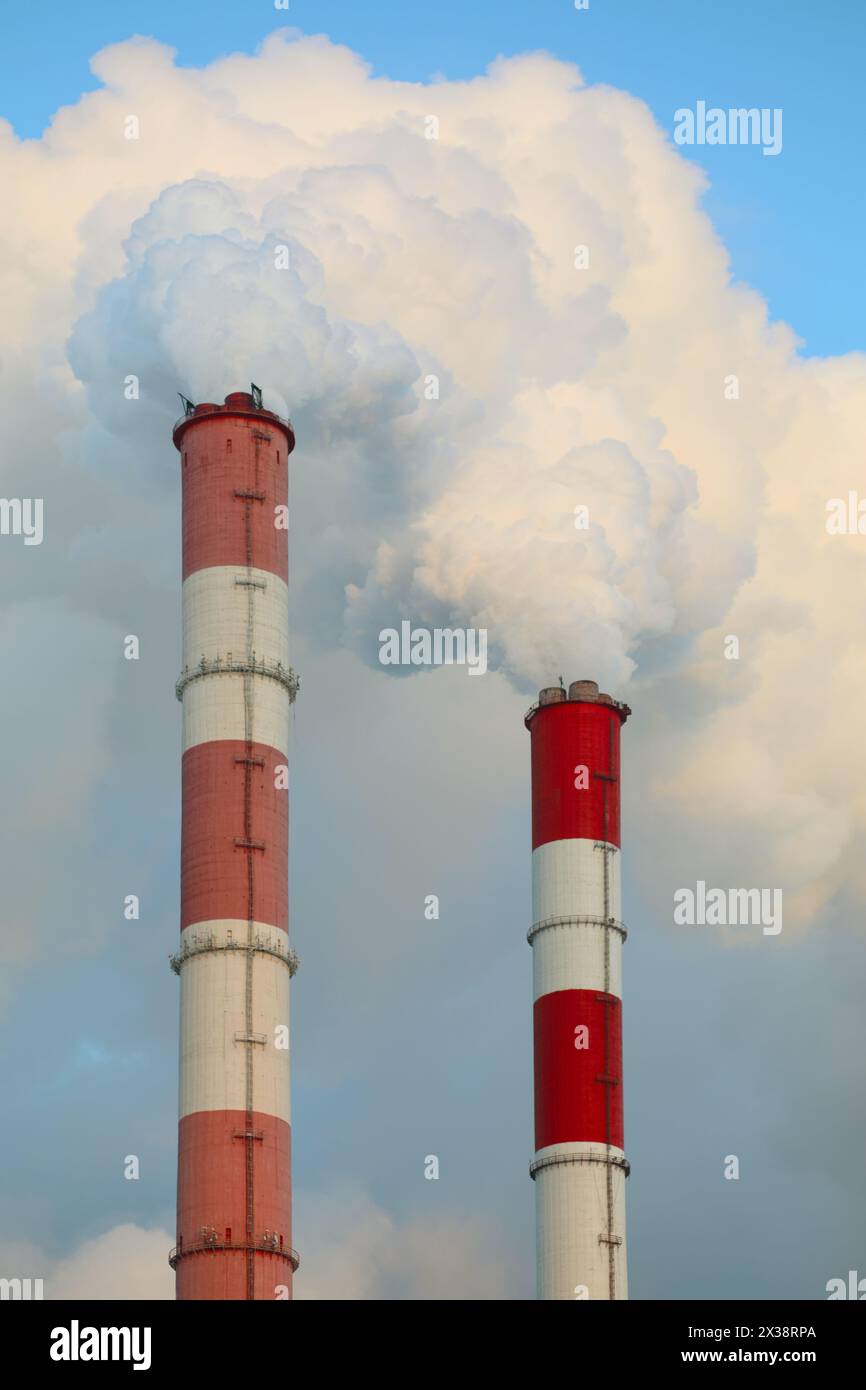 Zwei Pfeifen Fabrik und weißer Rauch am blauen Himmel am sonnigen Tag Stockfoto