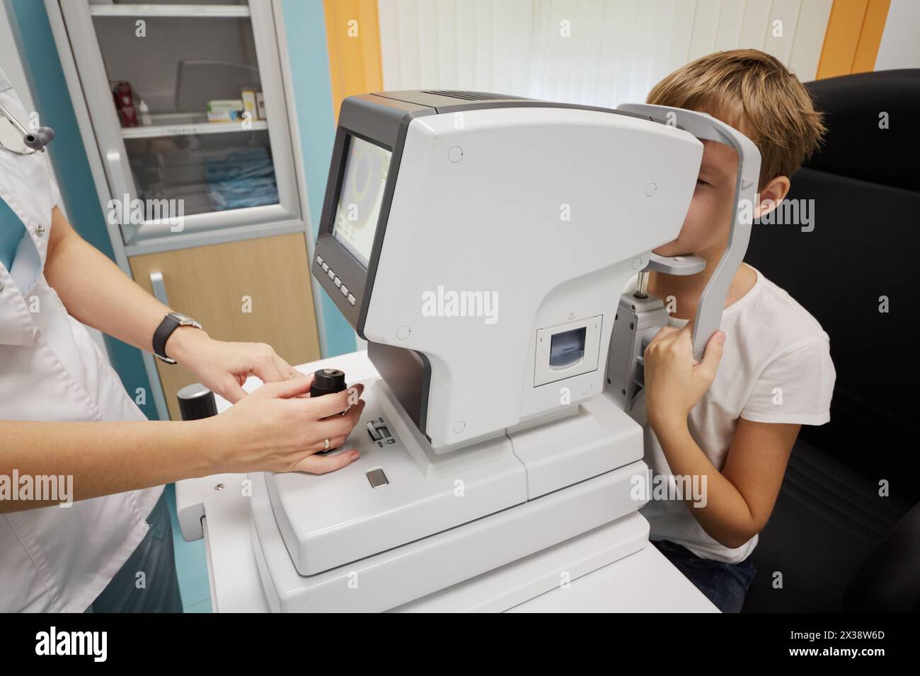 Die Ärztin untersucht die Augen eines Kindes mit Keratometer. Stockfoto