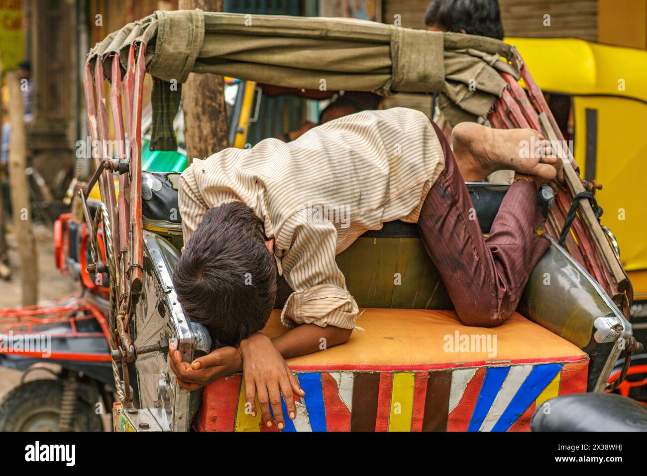 Junge, die auf dem Beifahrersitz einer Radrikscha in Varanasi, Indien, schlafen. Stockfoto