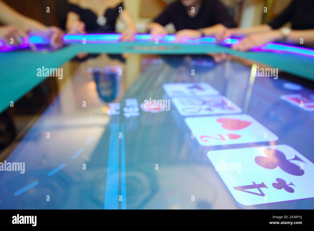 Elektronischer Tisch im modernen Casino und Hände von vier Spielern außer Fokus Stockfoto