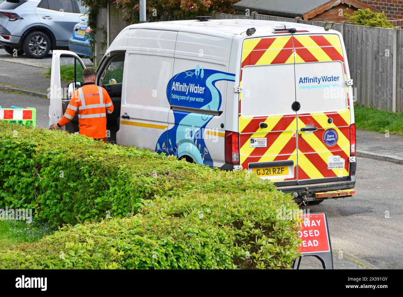 Affinity Water Engineer arbeitet an der Wasserversorgung des Kunden im Vorgarten, geparkt in Wohngegend, Rückansicht des Van in Essex England, Großbritannien Stockfoto