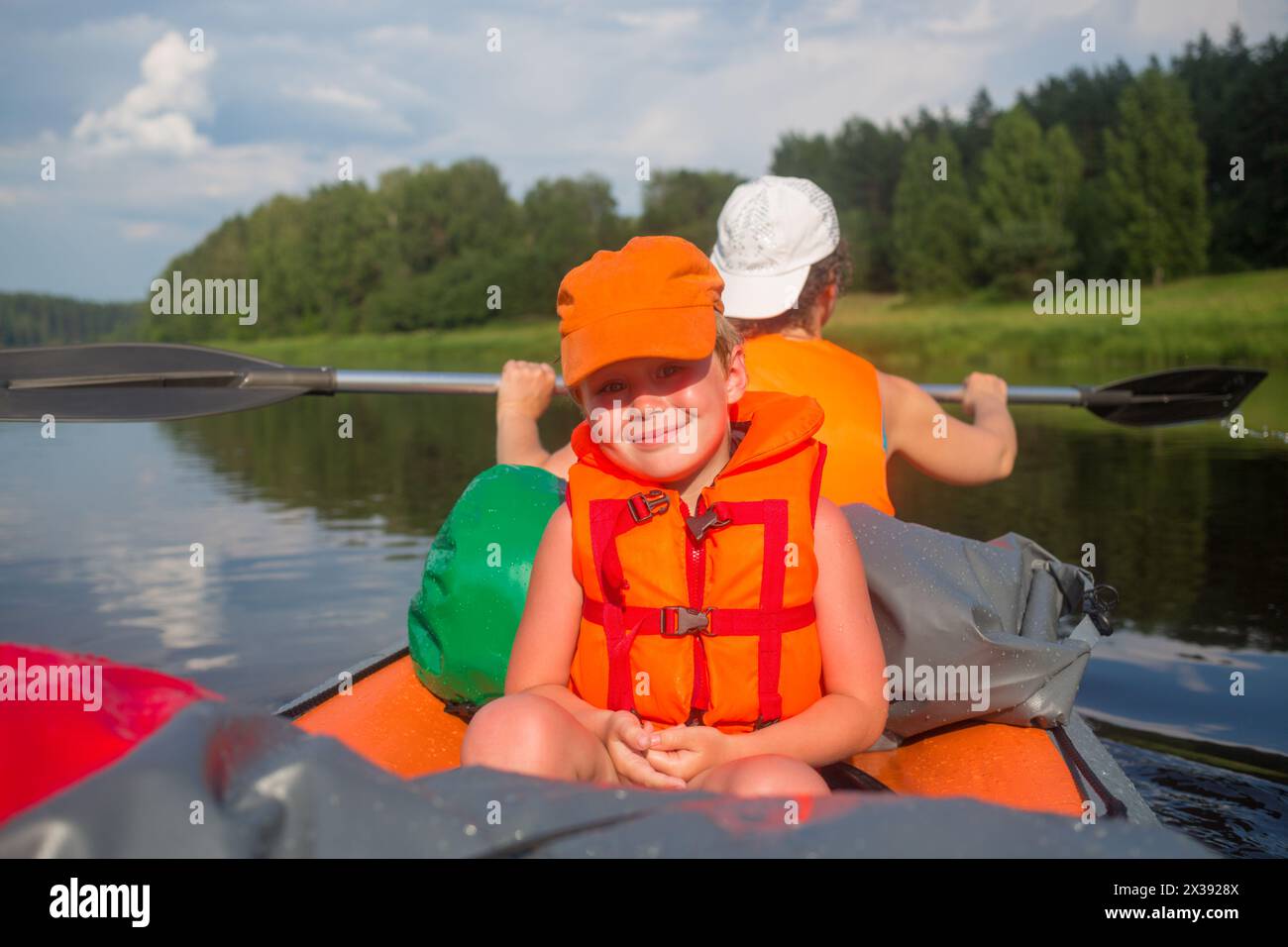 Glücklicher kleiner Junge und Frau in Schwimmwesten segeln im Sommer auf einem aufblasbaren Boot auf dem Fluss, konzentrieren Sie sich auf das Kind Stockfoto