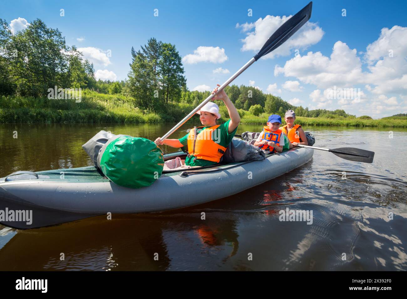 Zwei Frauen mit Rudern und einem kleinen Jungen segeln an sonnigen Sommertagen auf Schlauchbooten auf dem Fluss Stockfoto