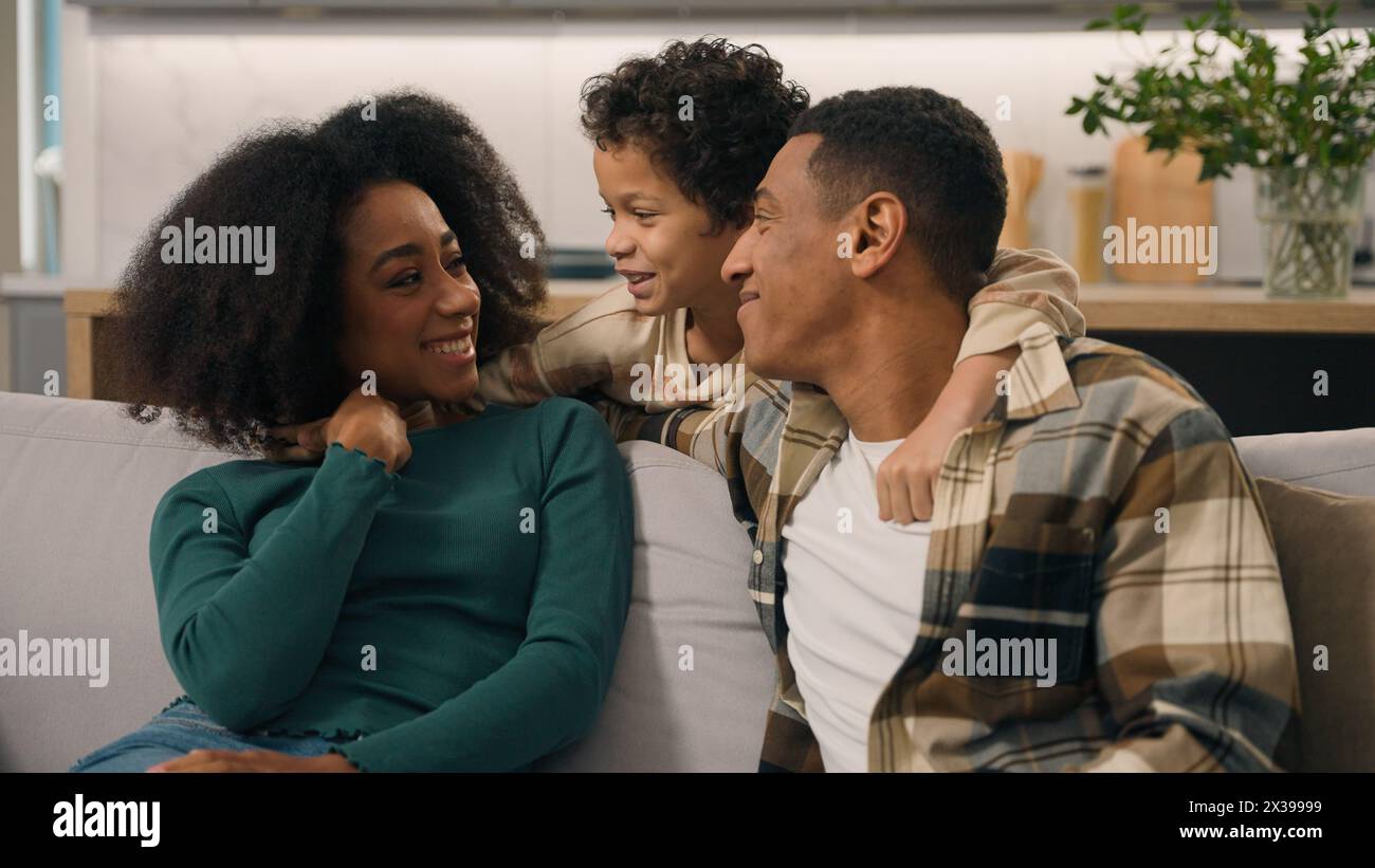Glückliche fröhliche afroamerikanische Familie Erwachsene Eltern verheiratete Paare Mutter Vater kleiner Junge entzückendes Kind Kind Kind Sohn, der Spaß hat, kuschelig umarmen zu reden Stockfoto