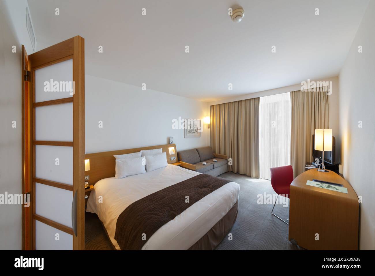 MONTE CARLO, MONACO - 3. August 2016: Novotel Hotel, schöne Einrichtung des Hotelzimmers, Schlafzimmer mit Aussicht, Sofa und Fernseher Stockfoto