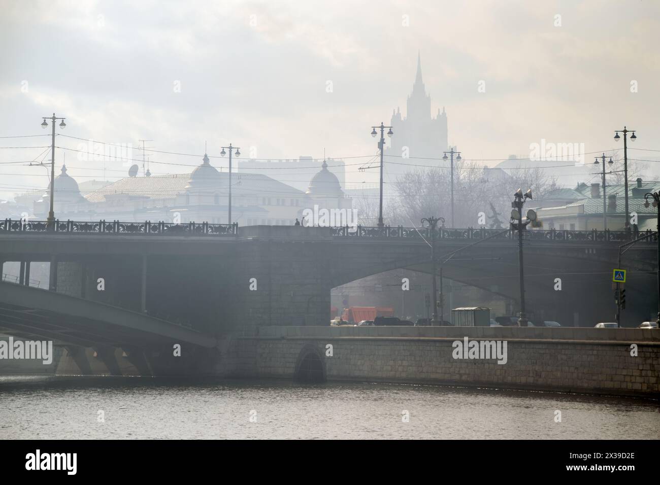 Große Steinbrücke mit Laternen im Nebel und Silhouette eines großen Gebäudes in Moskau Stockfoto