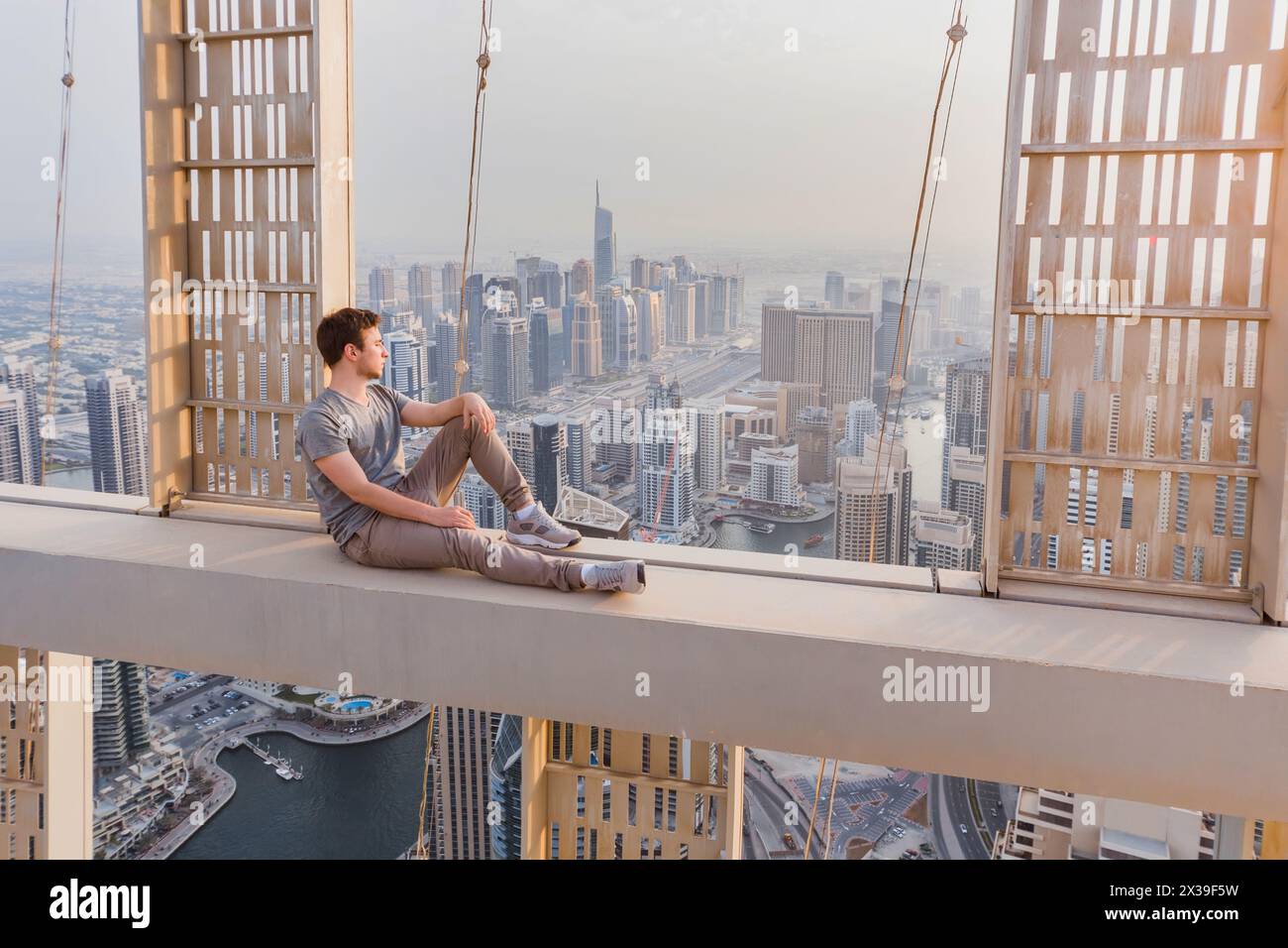 Dachdecker sitzt auf einem Betonquerträger des Cayan Tower (Infinity Tower) in Dubai, VAE Stockfoto