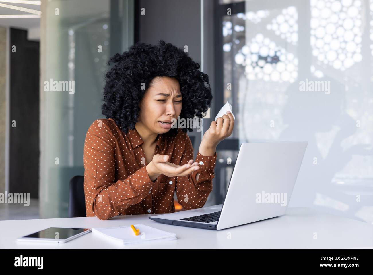 Eine beunruhigte Geschäftsfrau, die professionelle Hilfe durch eine Online-Beratung mit einem Psychotherapeuten sucht, sichtbar aufgebracht und Tränen abwischt. Stockfoto