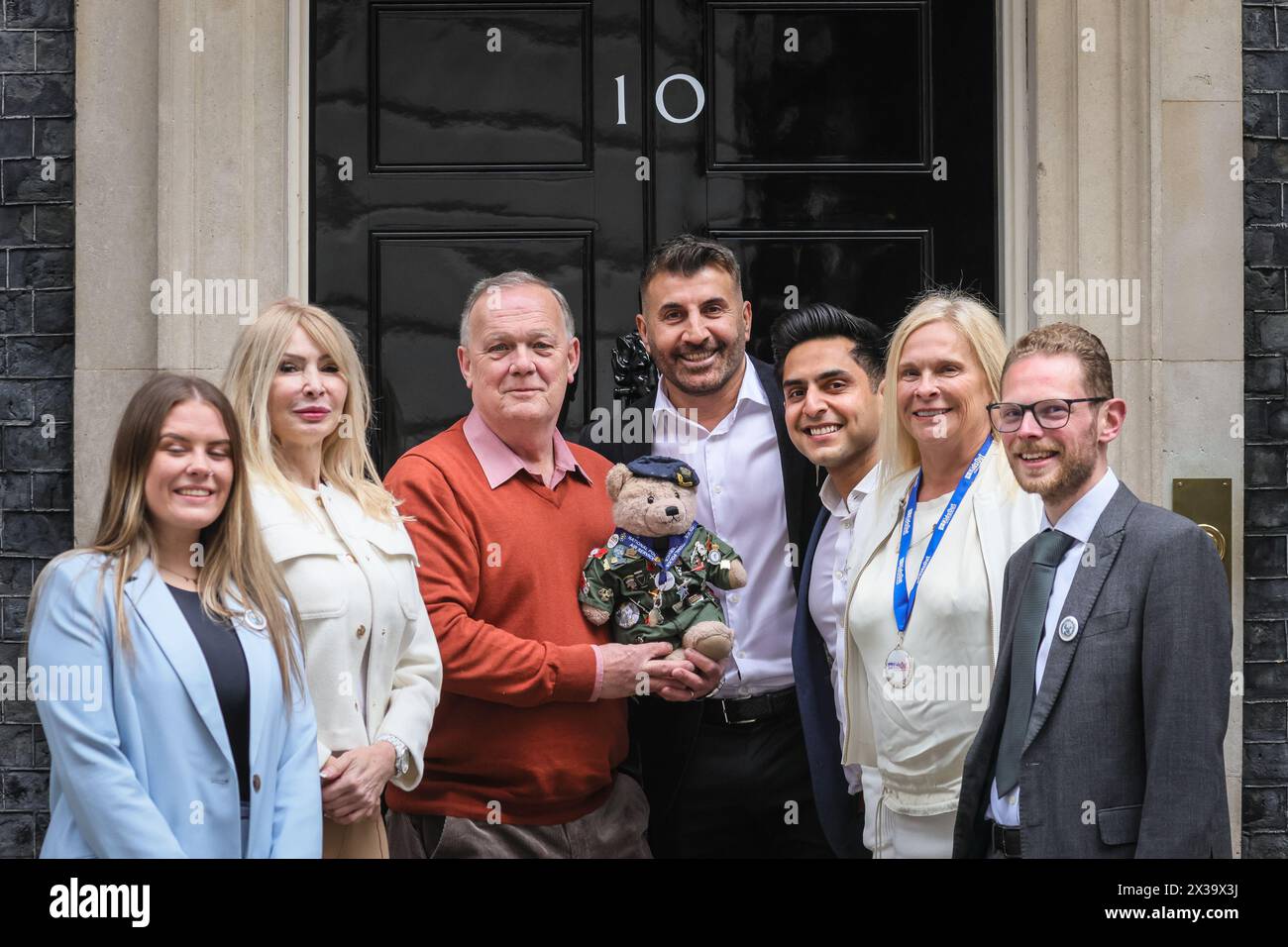 London, Großbritannien. April 2024. Richard Bland, Gründer Bear Force, Sara Williams, Kids Out CEO und andere mit dem Bear Force Maskottchen. Die Wohltätigkeitsorganisationen Bear Force und Kids Out haben heute Nachmittag einen Fotoanruf an der berühmten schwarzen No 10 Door in der Downing Street. Bear Force wurde gegründet, um Kinder jeden Alters zum Reden zu ermutigen, nach dem Selbstmord des Gründers Richard Bland Sohn. Kids Out ist eine Wohltätigkeitsorganisation, die Kinder und Mütter unterstützt, die in 650 Schutzhütten leben. Kinder, die Opfer von Misshandlungen und Traumata geworden sind, wollen das Leben der Kinder wieder glücklich machen. Quelle: Imageplotter/Alamy Live News Stockfoto