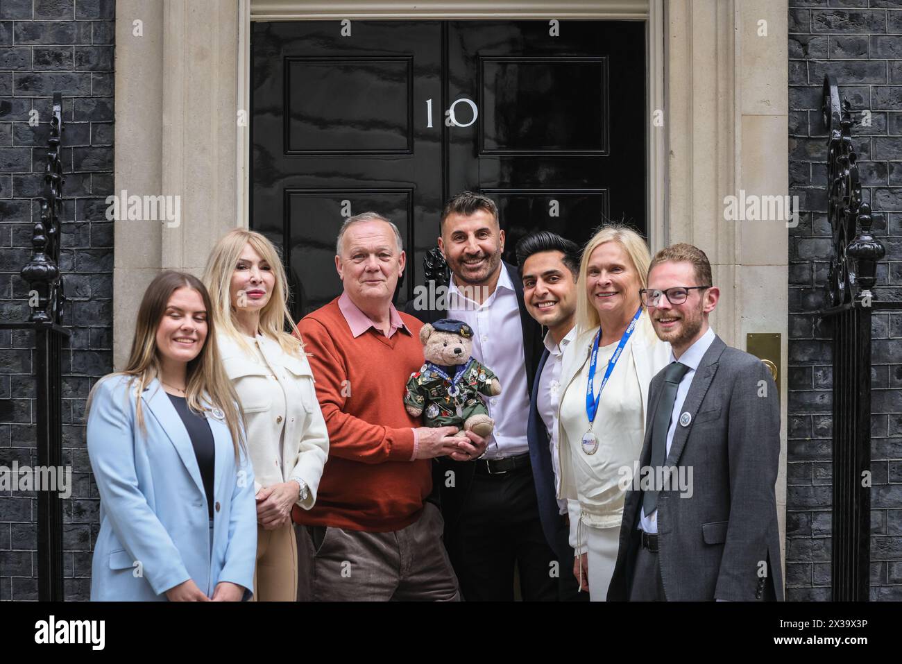 London, Großbritannien. April 2024. Richard Bland, Gründer Bear Force, Sara Williams, Kids Out CEO und andere mit dem Bear Force Maskottchen. Die Wohltätigkeitsorganisationen Bear Force und Kids Out haben heute Nachmittag einen Fotoanruf an der berühmten schwarzen No 10 Door in der Downing Street. Bear Force wurde gegründet, um Kinder jeden Alters zum Reden zu ermutigen, nach dem Selbstmord des Gründers Richard Bland Sohn. Kids Out ist eine Wohltätigkeitsorganisation, die Kinder und Mütter unterstützt, die in 650 Schutzhütten leben. Kinder, die Opfer von Misshandlungen und Traumata geworden sind, wollen das Leben der Kinder wieder glücklich machen. Quelle: Imageplotter/Alamy Live News Stockfoto