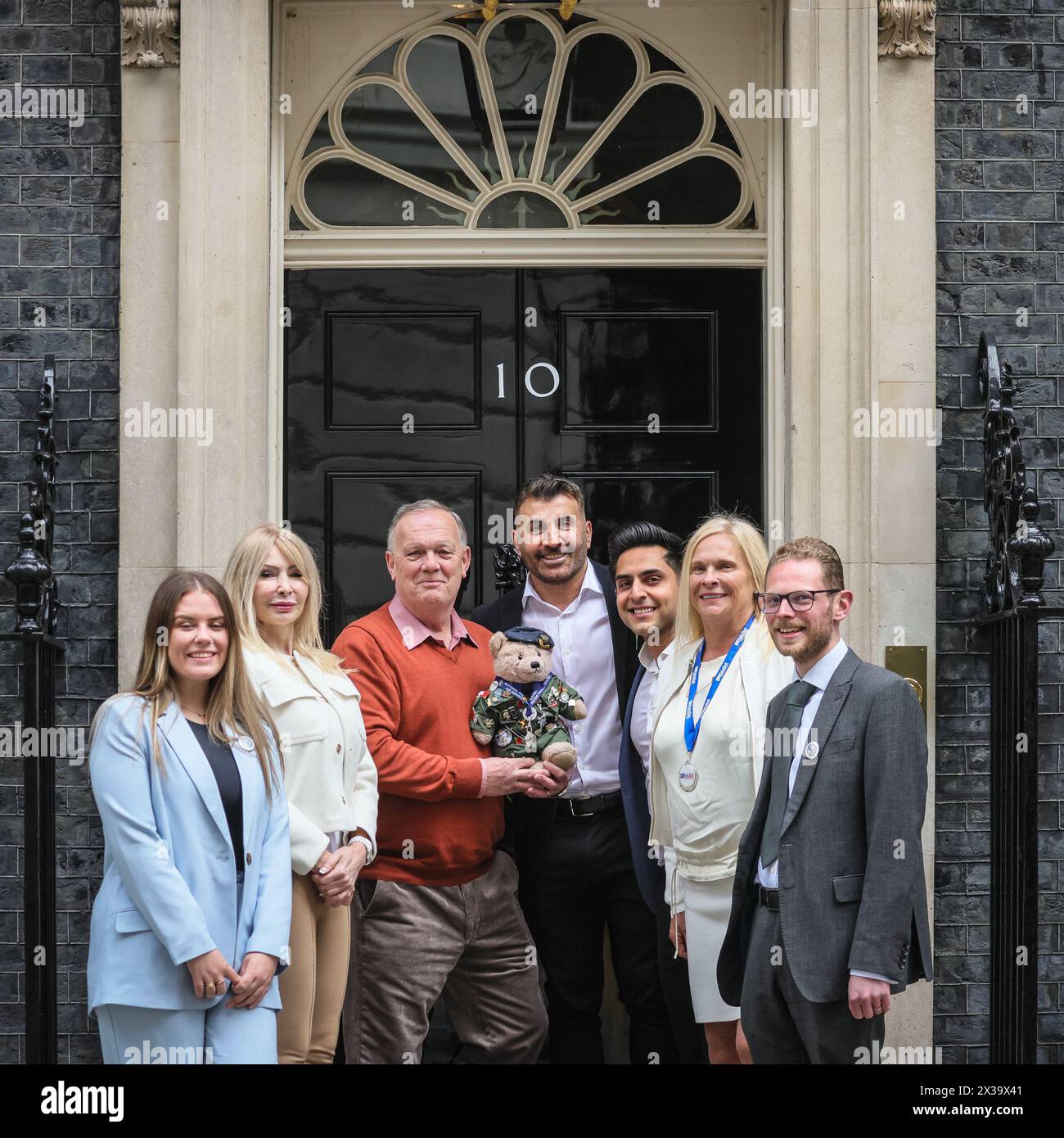 London, Großbritannien. April 2024. Richard Bland, Gründer Bear Force, Sara Williams, Kids Out CEO und andere mit dem Bear Force Maskottchen. Die Wohltätigkeitsorganisationen Bear Force und Kids Out haben heute Nachmittag einen Fotoanruf an der berühmten schwarzen No 10 Door in der Downing Street. Bear Force wurde gegründet, um Kinder jeden Alters zum Reden zu ermutigen, nach dem Selbstmord des Gründers Richard Bland Sohn. Kids Out ist eine Wohltätigkeitsorganisation, die Kinder und Mütter unterstützt, die in 650 Schutzhütten leben. Kinder, die Opfer von Misshandlungen und Traumata geworden sind, wollen das Leben der Kinder wieder glücklich machen. Quelle: Imageplotter/Alamy Live News Stockfoto