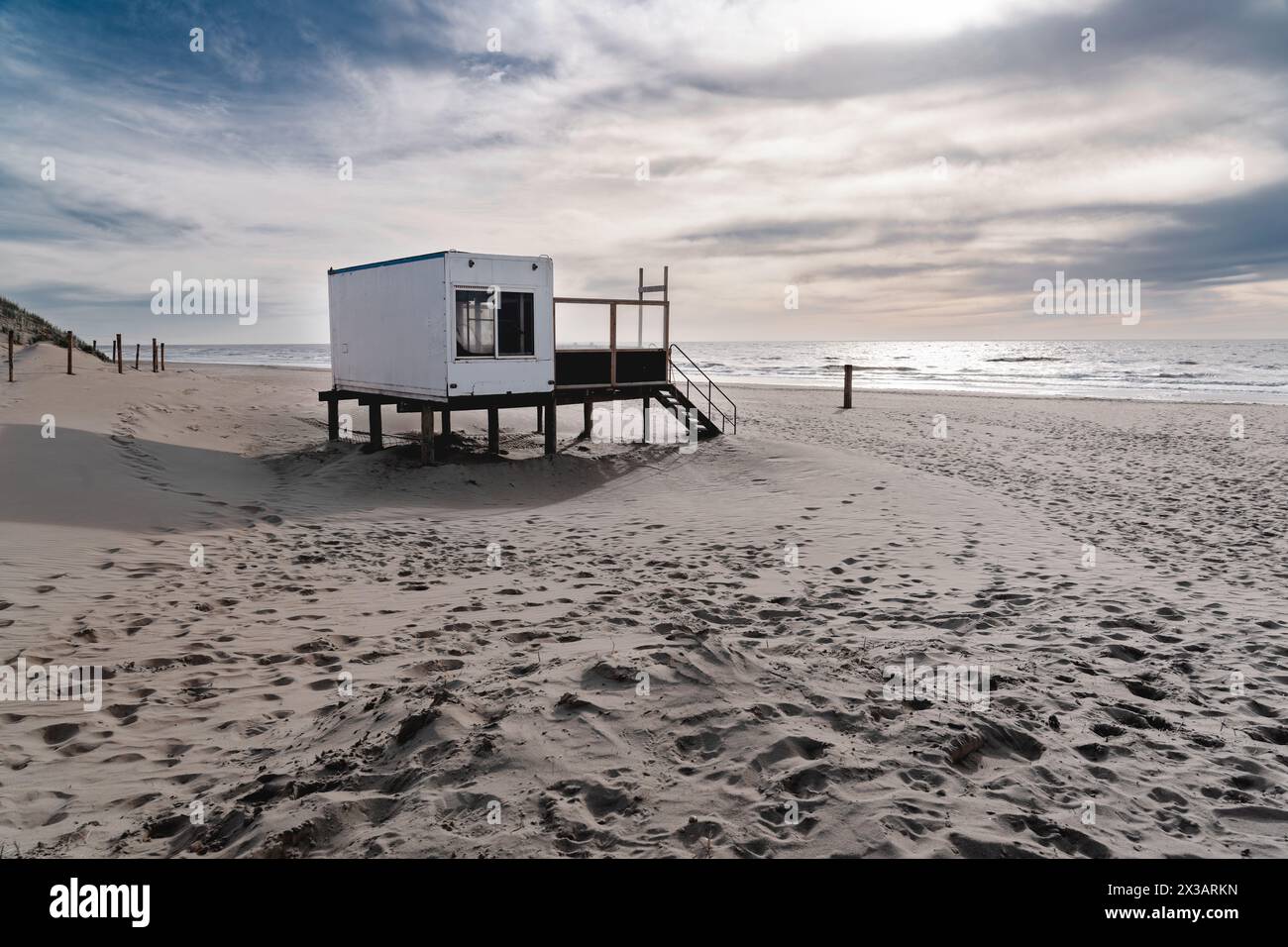 Ruhiger Strand in der Dämmerung mit verlassener Rettungshütte. Eine ruhige Strandszene mit Holzstruktur mit Blick auf das ruhige Meer, während das Abendlicht verblasst Stockfoto