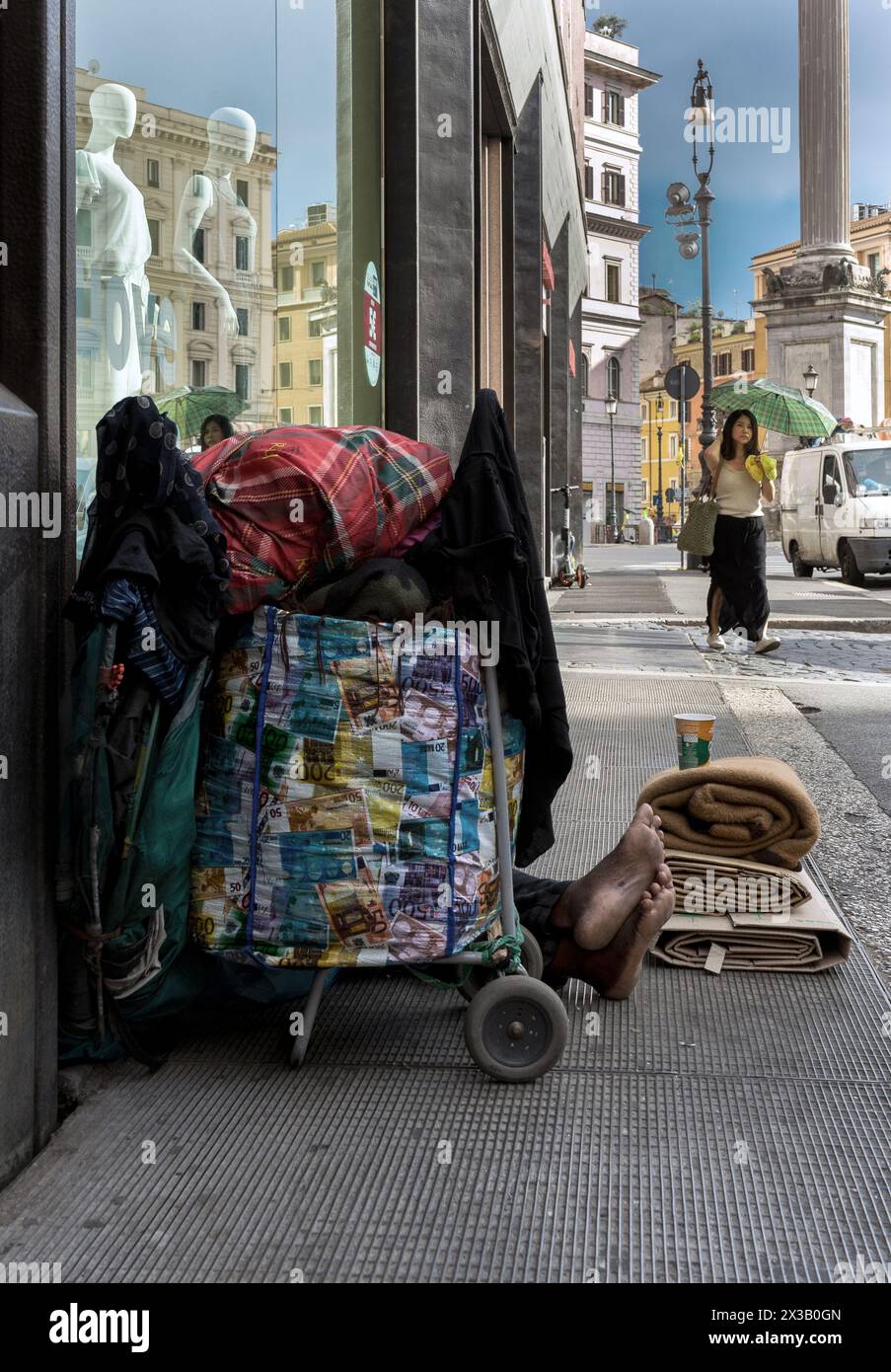 Italien, Rom: Ein Obdachloser sitzt auf dem Bürgersteig, geschützt von einem Trolley, der Euro-Banknoten von unterschiedlichem Wert darstellt Stockfoto