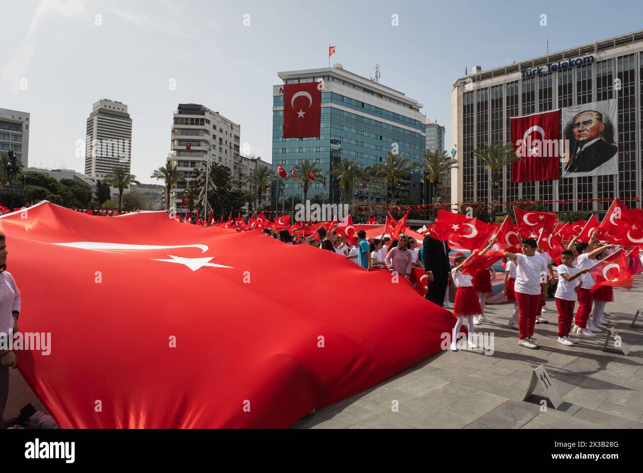 Izmir, Türkei - 23. April 2024: Während des Tages der nationalen Souveränität und des Kindertages, strecken Kinder eine riesige türkische Flagge auf dem Platz der Republik Izmir, Stockfoto