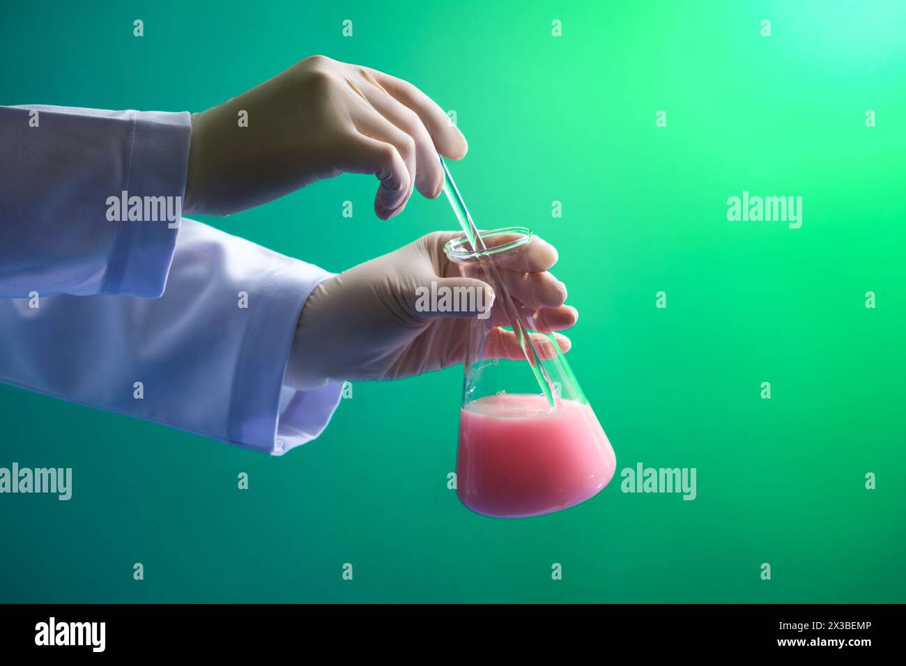 Wissenschaftler mit weißen Handschuhen rührt die Chemikalie mit einem Glasstab um. Medizingerätes Experiment und chemisch-biologisches Studium in wissenschaftlichen Laboren Stockfoto