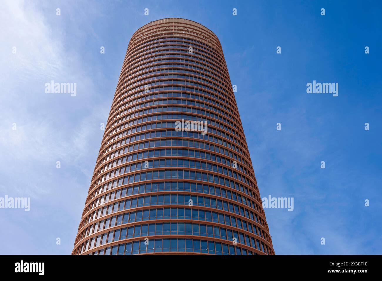 Nahaufnahme eines zylindrischen Wolkenkratzers mit gemusterter Fassade unter blauem Himmel, Torre Sevilla, Sevilla, Andalusien, Spanien Stockfoto