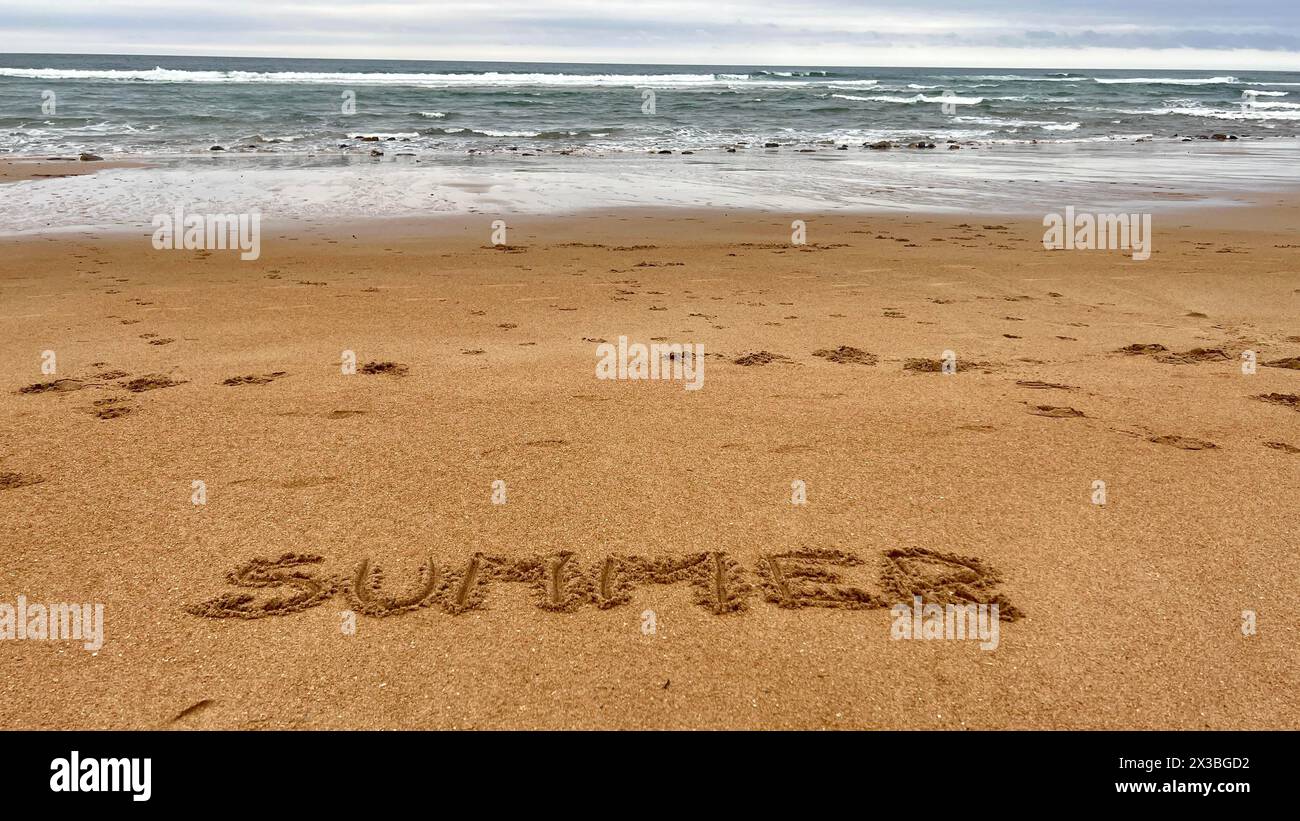 Blick auf die Küste am Strand mit dem Wort SOMMER in den Sand geschrieben. Urlaub, Sommer, Entspannung, Reisen, Trennung, Genuss Stockfoto