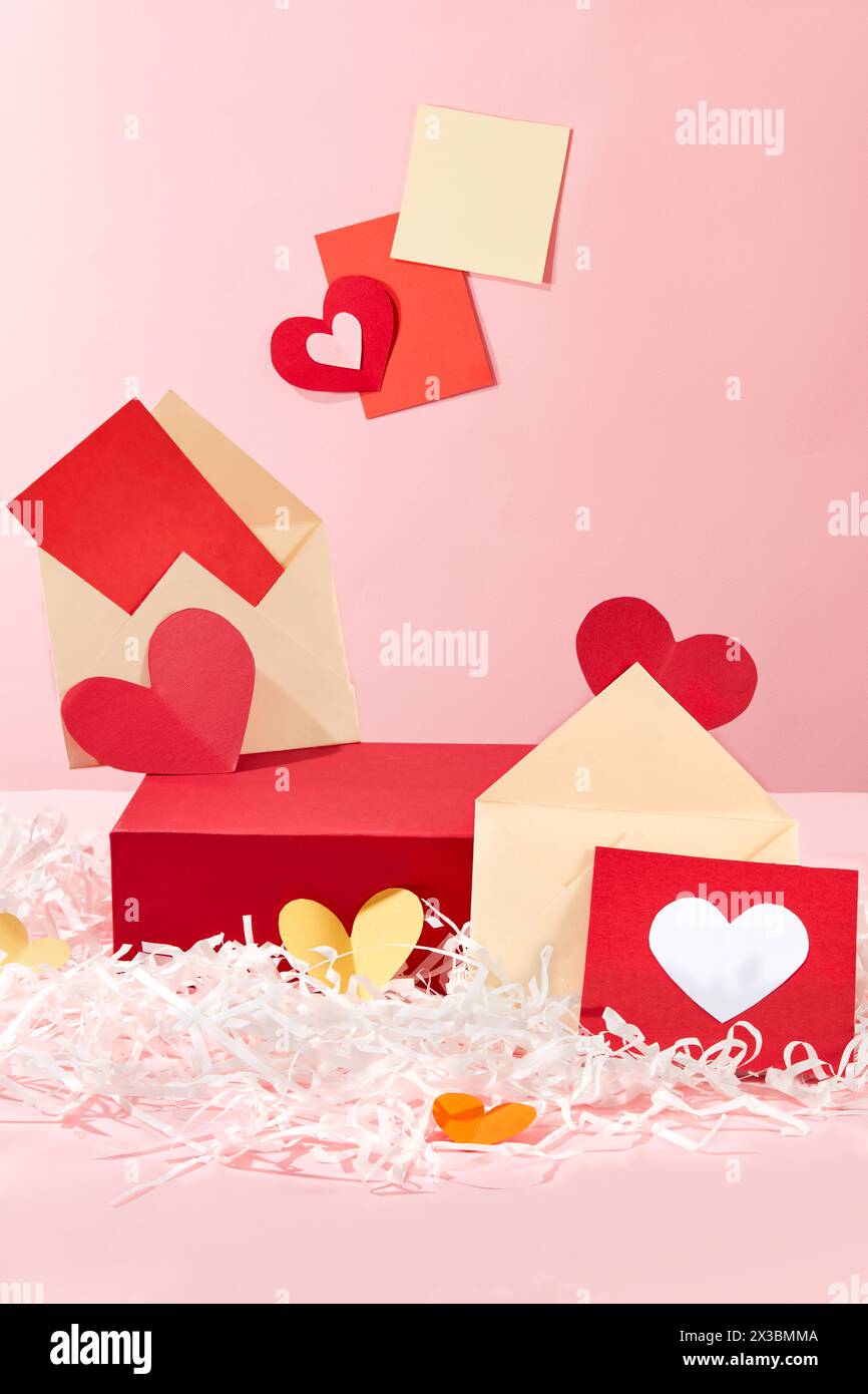 Leeres Podium in rechteckiger Form mit mehreren Umschlägen und Geschenkkarten. Notizpapier auf rosafarbenem Hintergrund. Modell für Ausstellungen oder Stockfoto