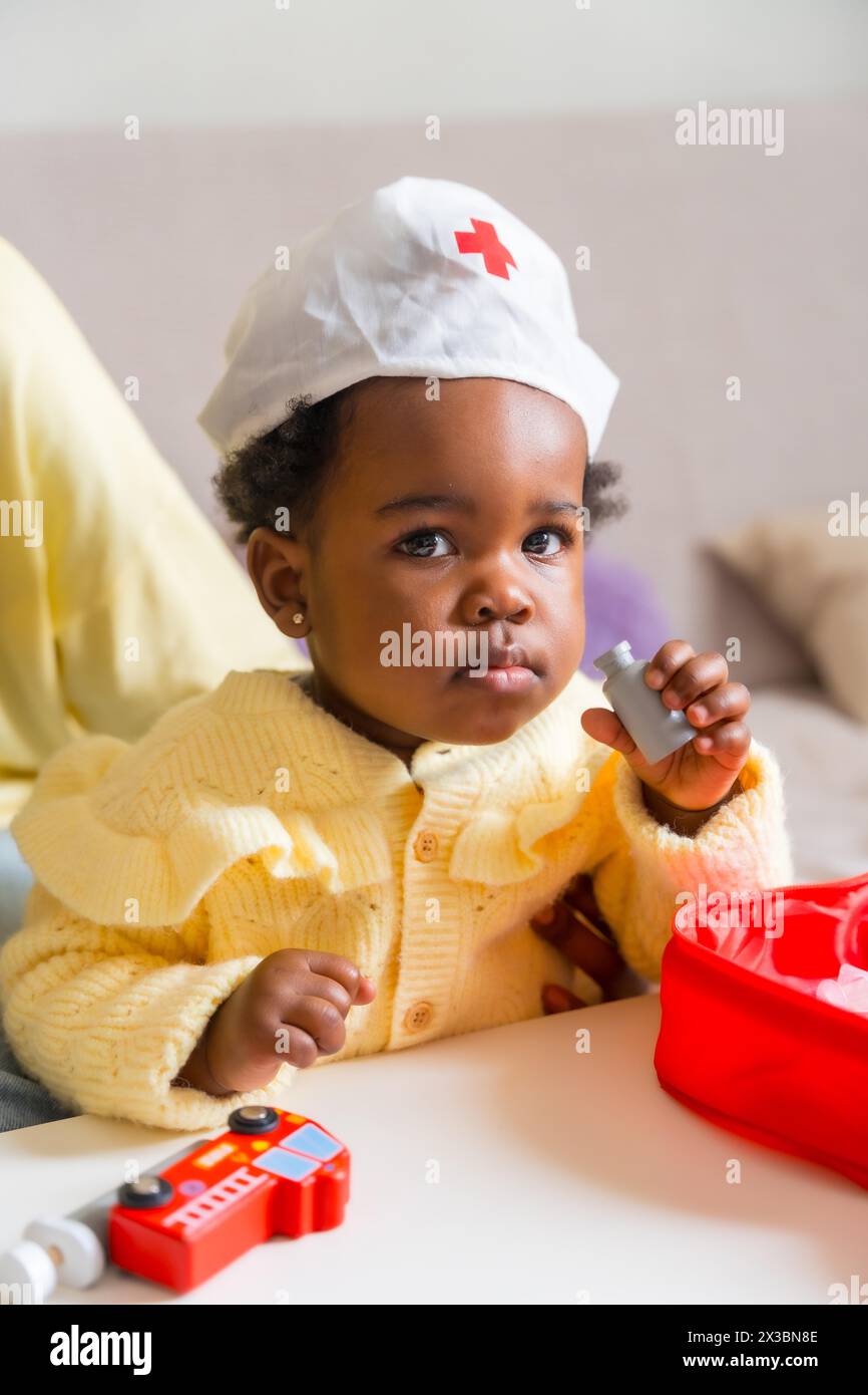 Vertikales Foto eines bezaubernden afrikanischen Kindes, gekleidet wie ein Arzt, der zu Hause spielt Stockfoto