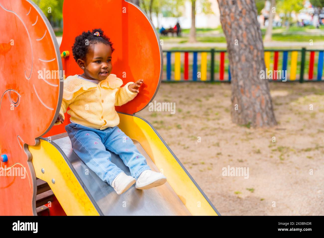 Afrikanisches Mädchen spielt auf einer Rutsche auf einem öffentlichen Spielplatz Stockfoto