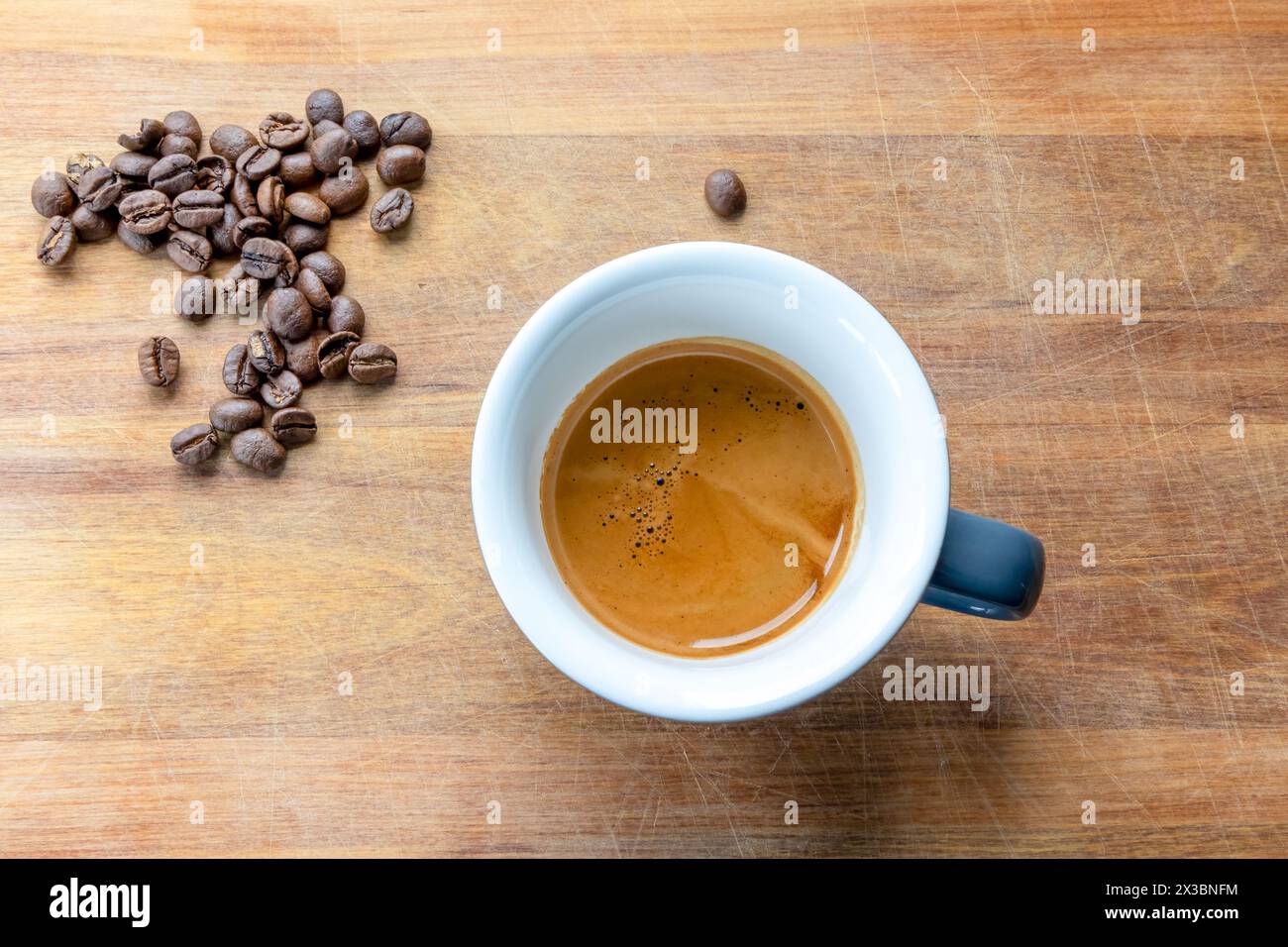 Ein doppelter Espresso auf einem Holzbrett mit frisch gerösteten Kaffeebohnen. Stockfoto