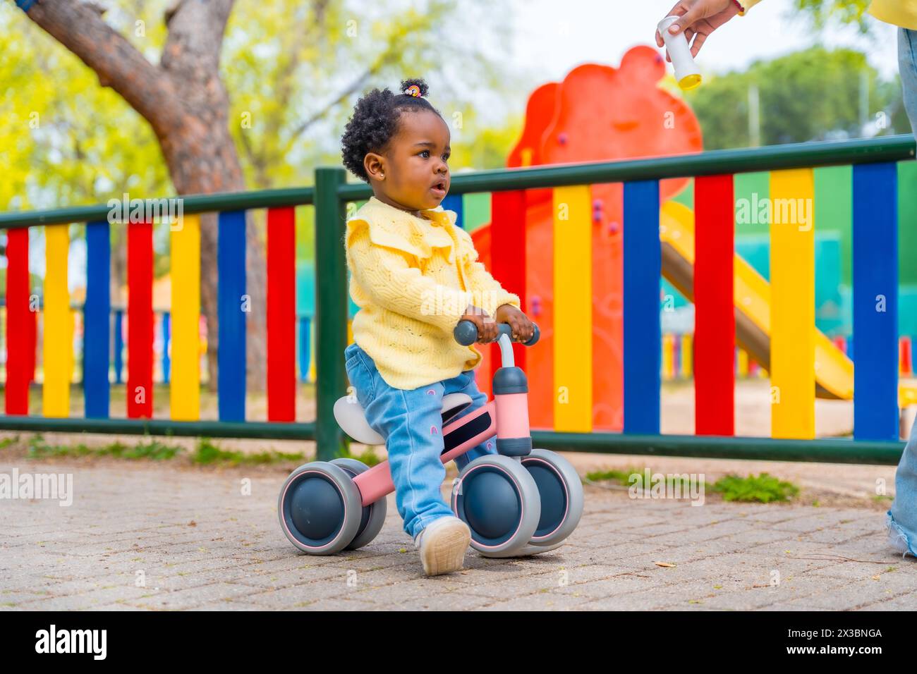 Foto in voller Länge von einem niedlichen afrikanischen Mädchen, das in einem Park auf einem Spielrad fährt Stockfoto