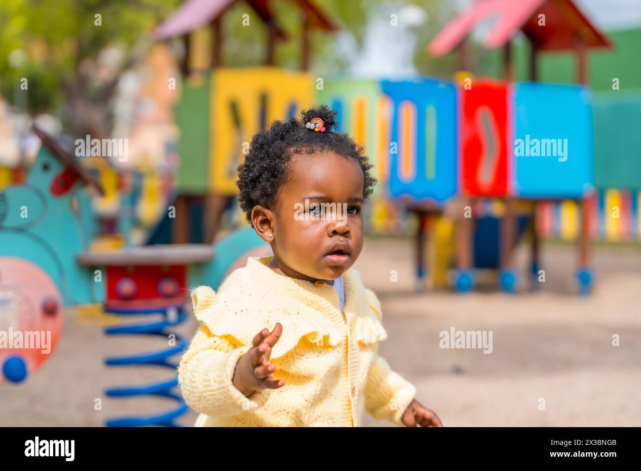 Ein kleines afrikanisches Mädchen, das auf dem Spielplatz unter der Sonne spielt Stockfoto