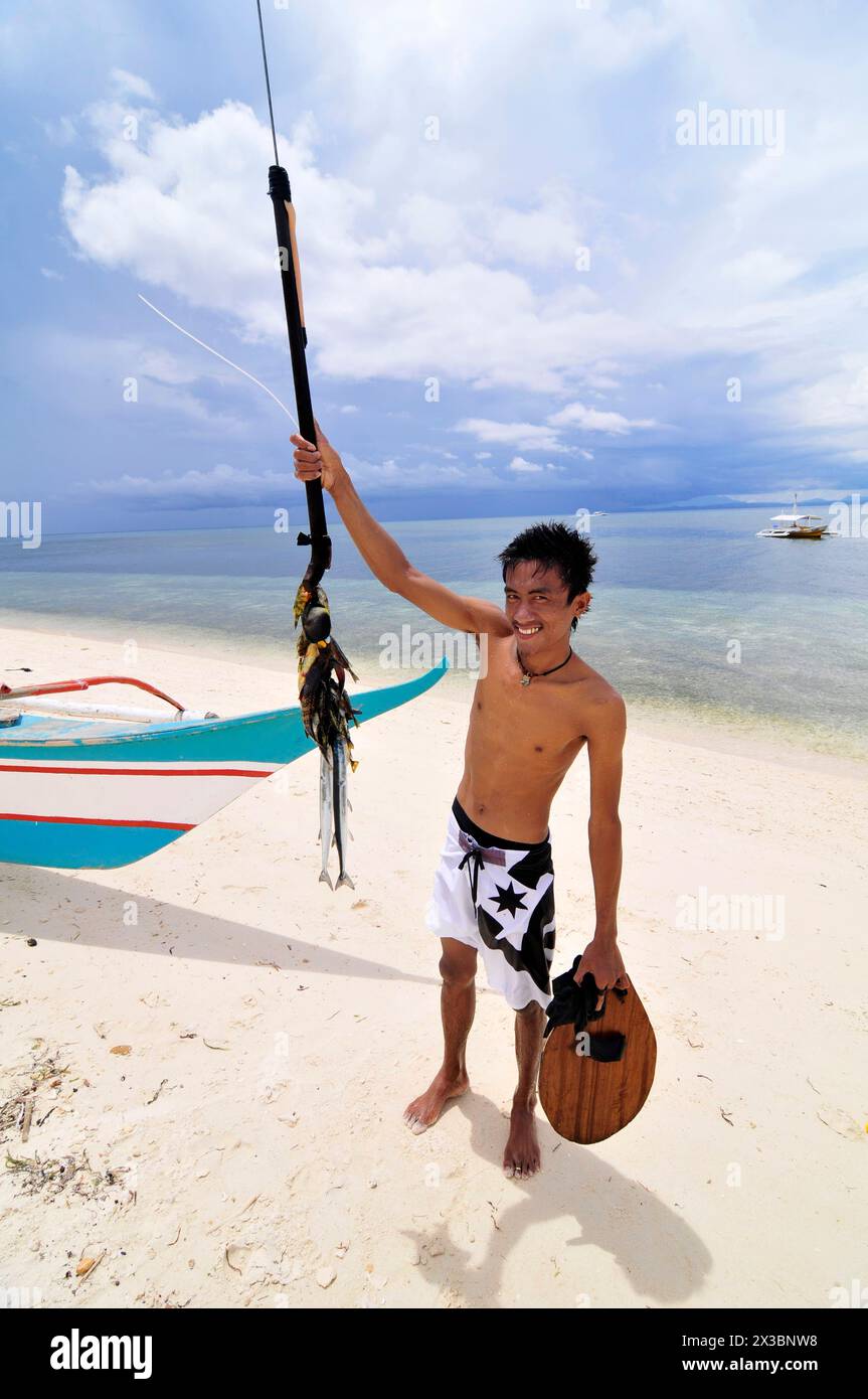 Ein philippinischer Mann zeigt seinen gefangenen Fisch auf einem Speer. Malapascua Island, Central Visayas, Philippinen. Stockfoto