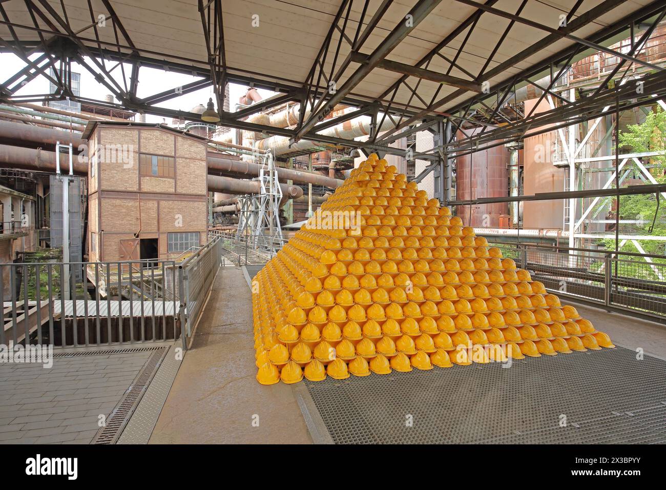 Pyramide mit gelben Schutzhelmen in der Erzhalle UNESCO Voelklinger Hütte, Innenansicht, Pyramide, Arbeitskleidung, Helme, gelb, Stapel, Stapel Stockfoto