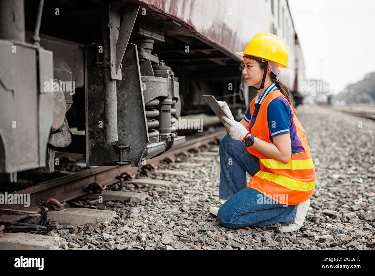 Lokomotivingenieur weibliche Arbeiter. Junge Teenager Asiatische Arbeitsüberprüfung Service Wartung Zug mit Tablet Computer Software. Stockfoto