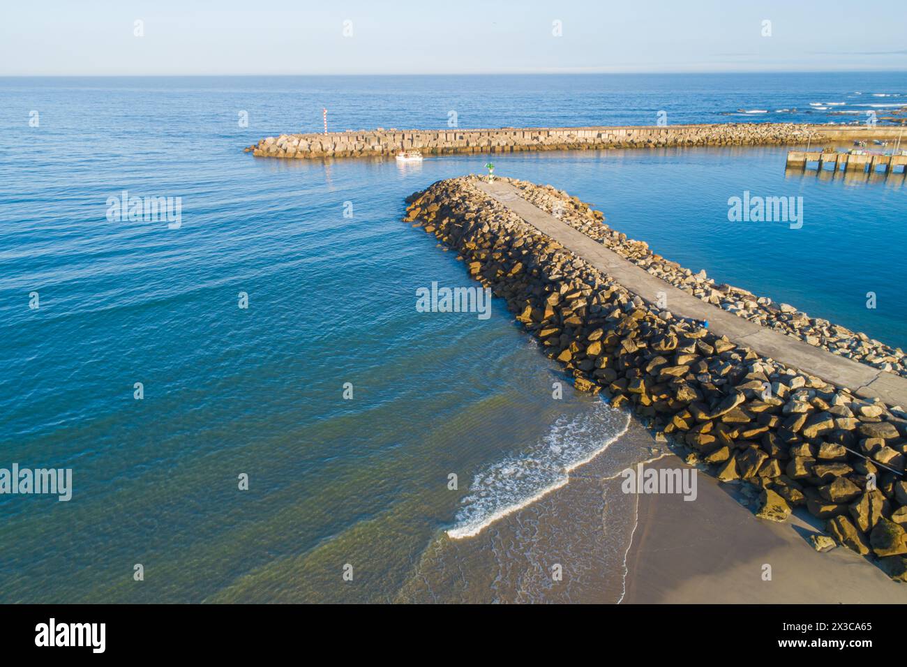 Drohnenansicht eines Schiffes, das von einem geschützten Hafen aus segelt Stockfoto