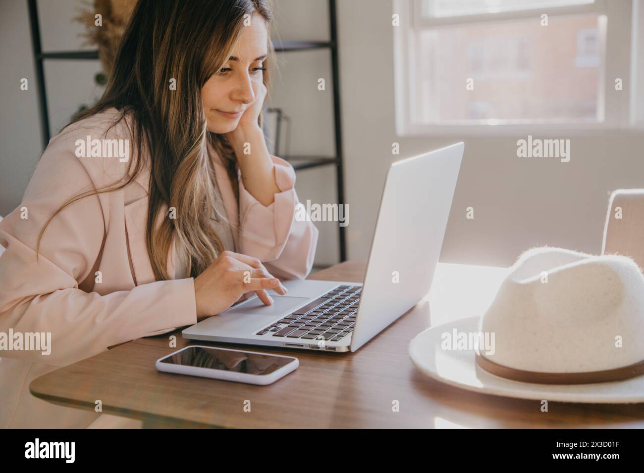 Frau in rosa Blazer konzentriert sich auf die Arbeit mit dem Notebook. Stockfoto