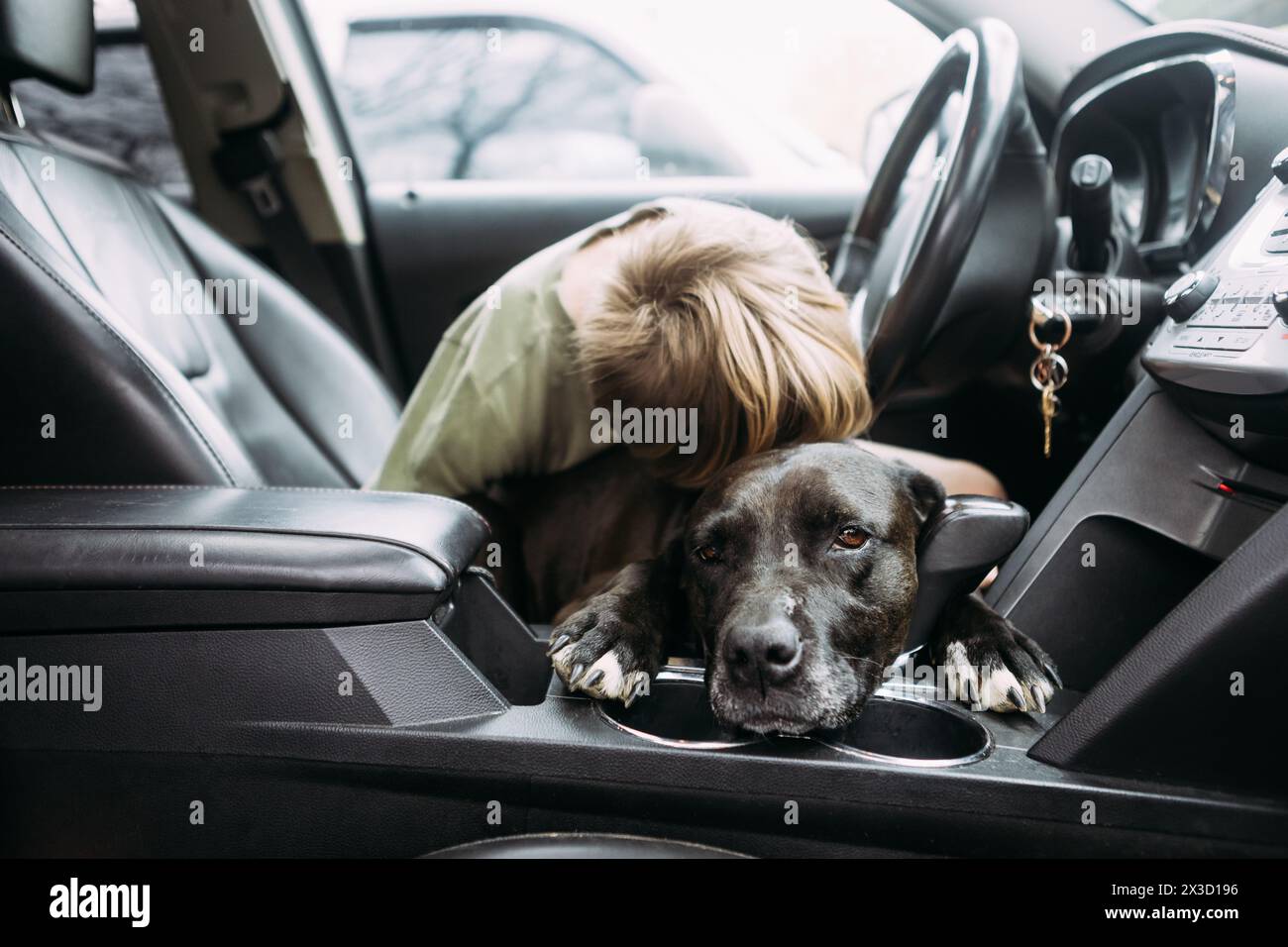 Süße Umarmung in einem Auto, der Junge umarmt seinen treuen Hund Stockfoto