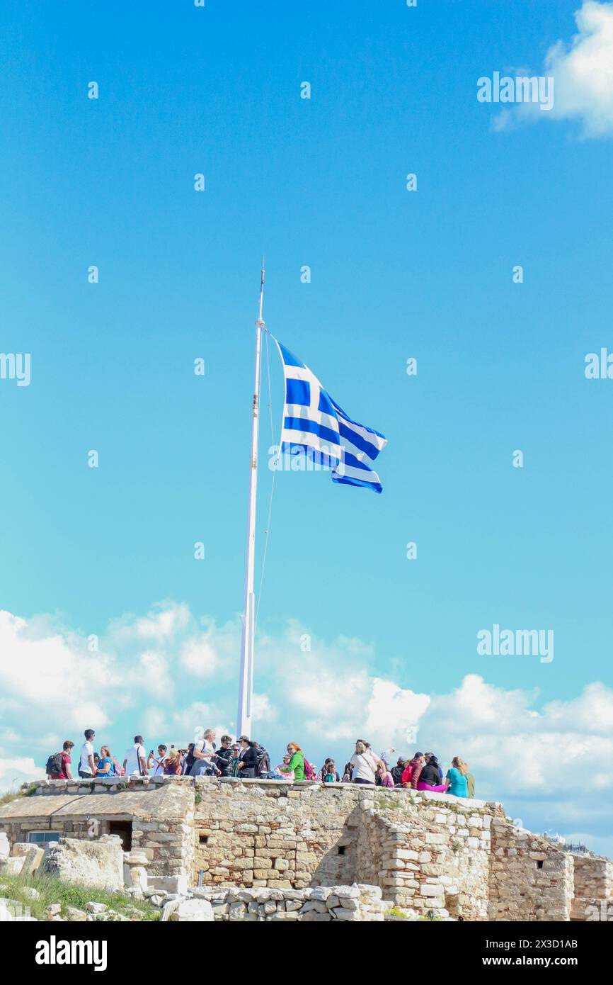 Als Symbol des Nationalstolzes winkt die griechische Flagge majestätisch vor dem Hintergrund des klaren blauen Himmels auf der Akropolis und verkörpert den Geist von h Stockfoto
