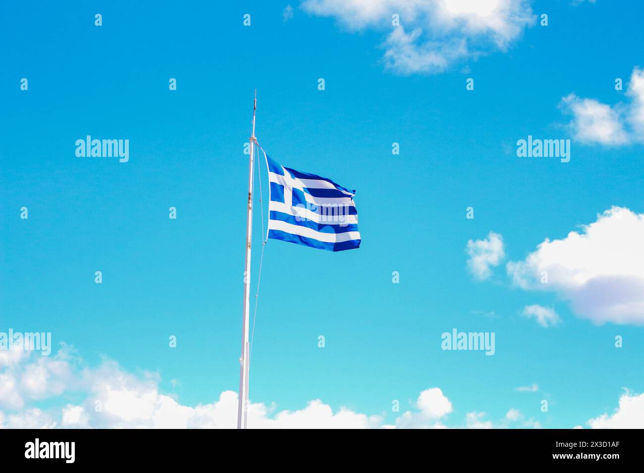 Als Symbol des Nationalstolzes winkt die griechische Flagge majestätisch vor dem Hintergrund des klaren blauen Himmels auf der Akropolis und verkörpert den Geist von h Stockfoto