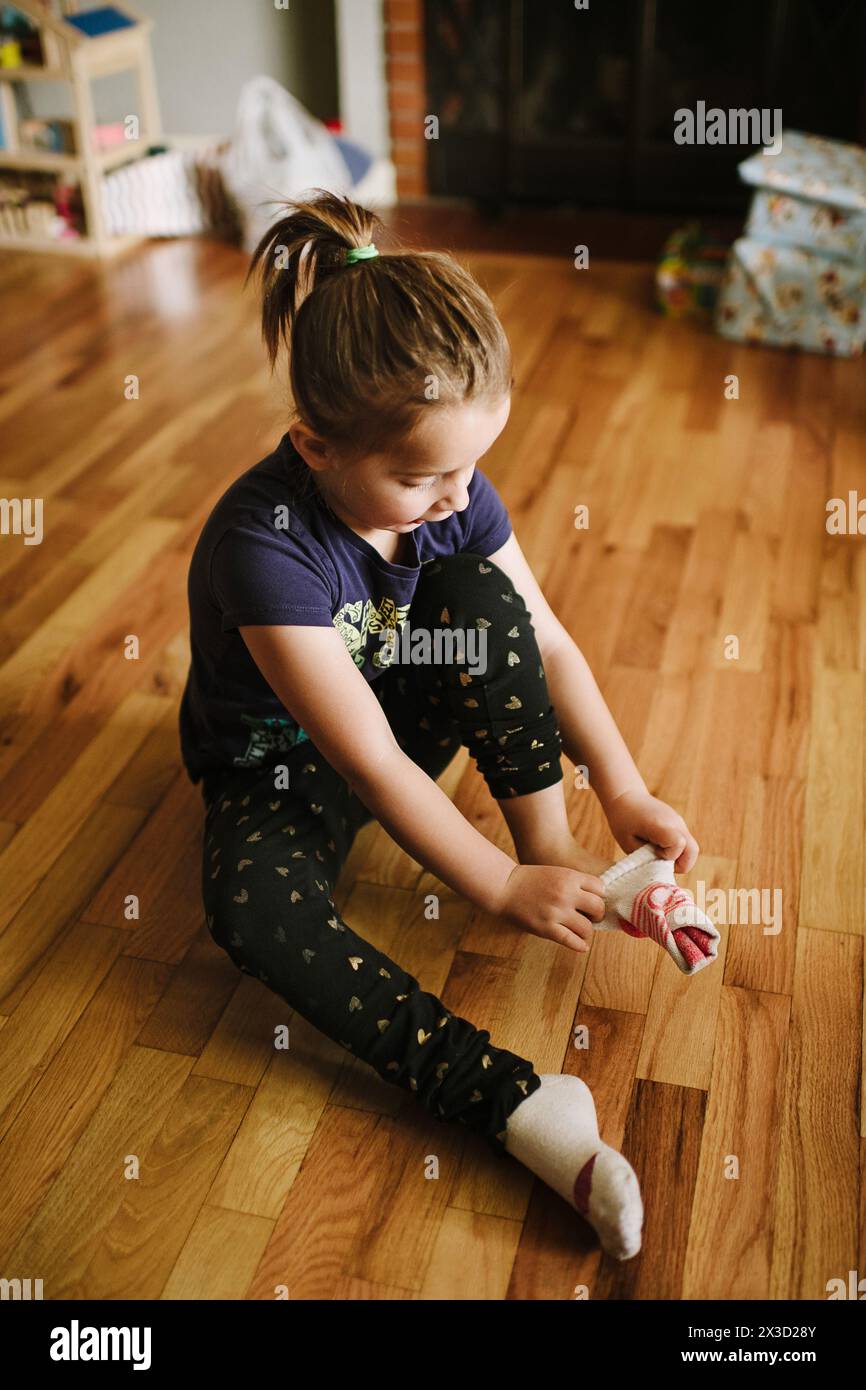 6-jähriges Mädchen zieht Socken an Stockfoto