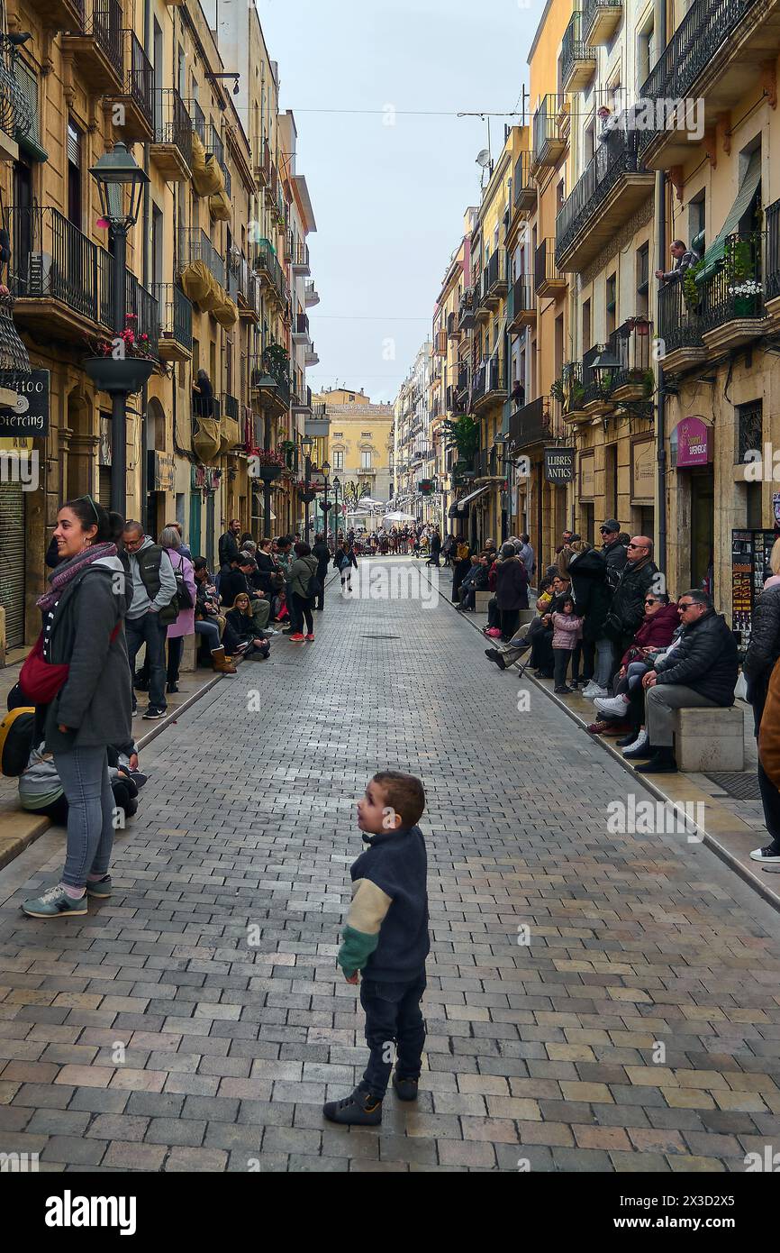 Tarragona, Spanien - 26. April 2024: Ein eindrucksvoller Blick auf eine Straße in Tarragona während der Karwoche zeigt die Zuschauer entlang historischer Gebäude Stockfoto