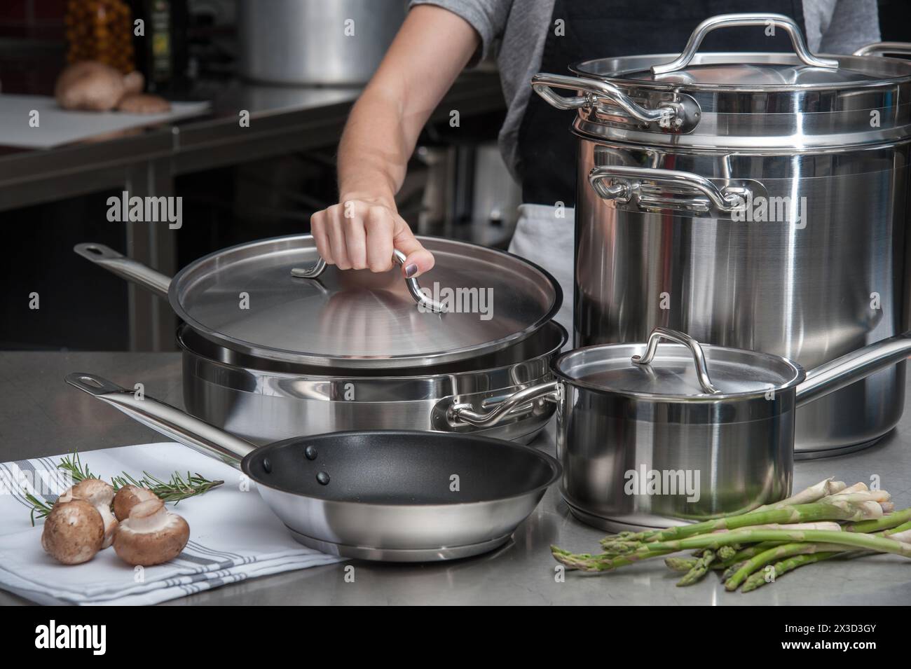 Küchenchef arbeitet mit Edelstahl-Kochgeschirr und frischen Produkten Stockfoto