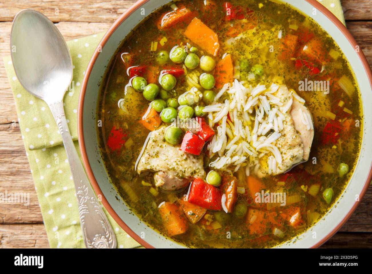 Aguadito de Pollo peruanische Suppe mit Koriander, Gemüse und Hühnchen aus der Nähe auf der Schüssel auf dem Holztisch. Horizontale Draufsicht von oben Stockfoto