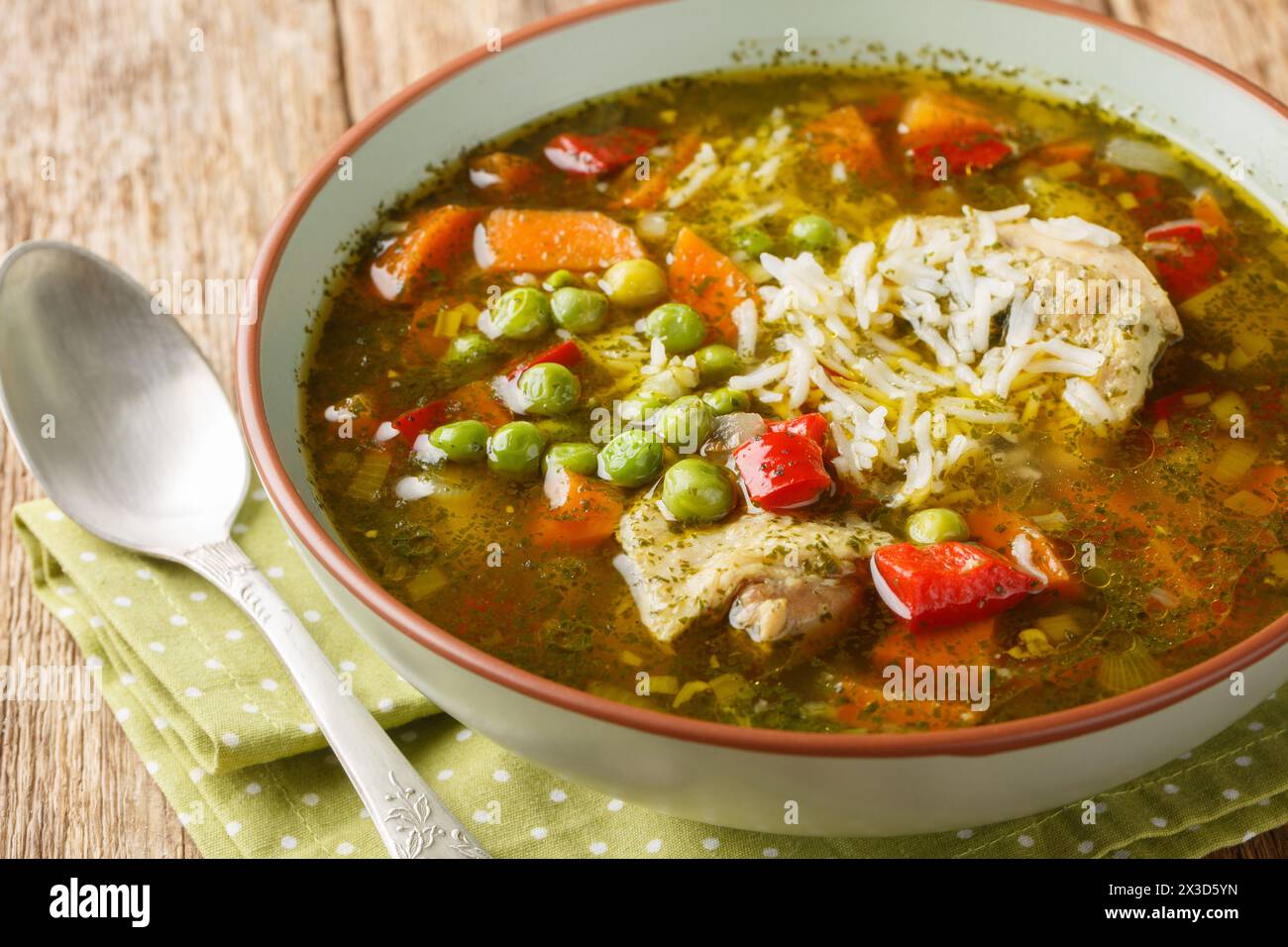 Peruanische Koriander-Hühnersuppe oder Aguadito de Pollo mit Reis und Gemüse in der Nähe auf der Schüssel auf dem Holztisch. Horizontal Stockfoto